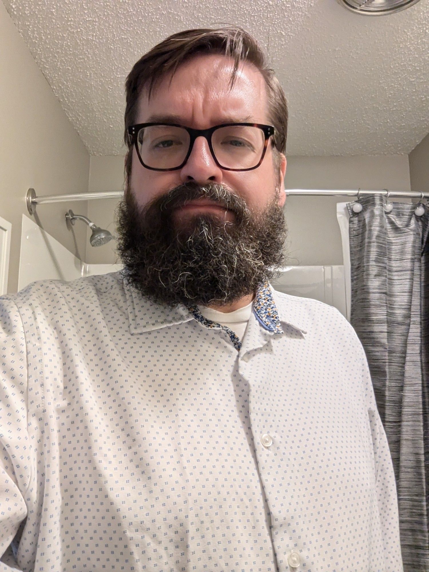 A bearded man in a nice, kinda dressy white shirt.