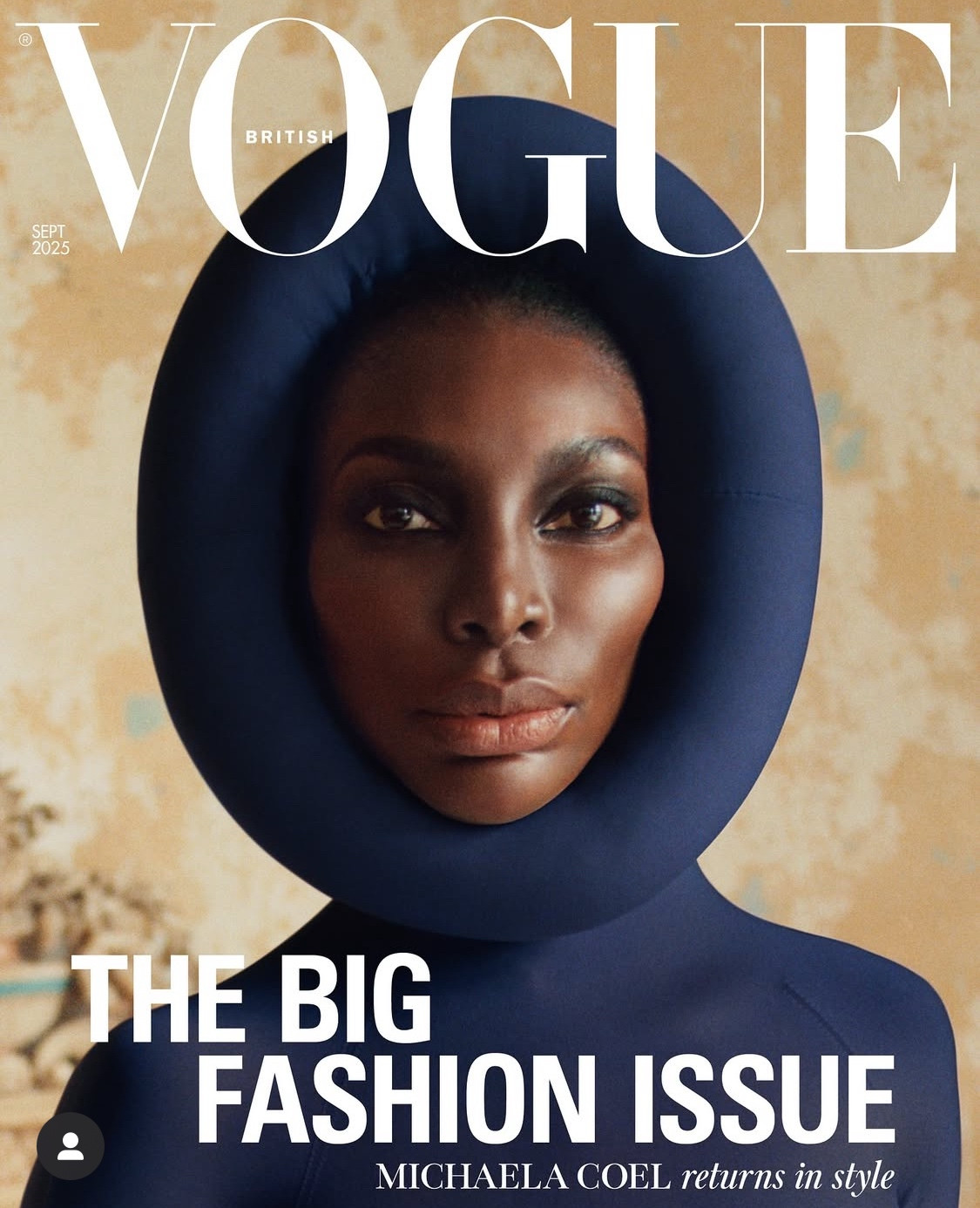 Michaela Coel on the cover of British Vogue. She is wearing a dark blue headpiece. 