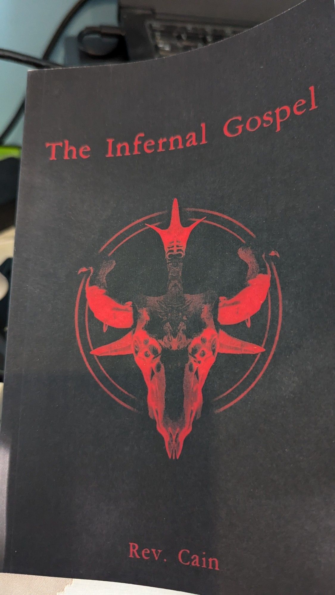 Photo of the book. All red and black, naturally. Baphomet-esque skull over red circles.