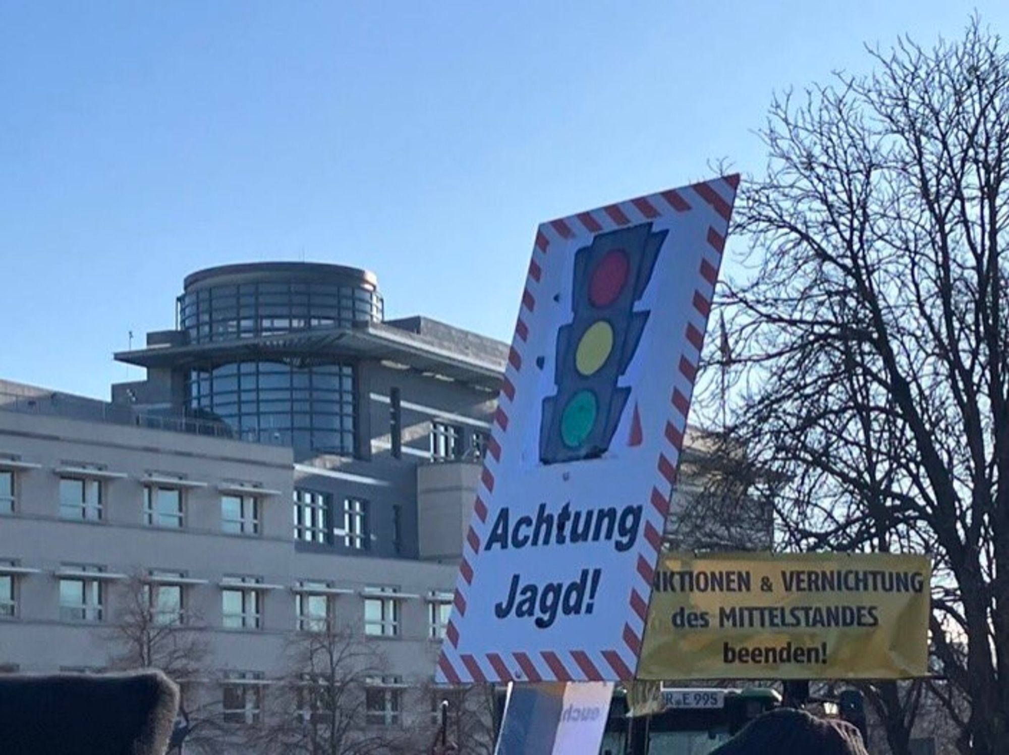 Weißes Schild mit roter Umrandung, darauf abgebildet ist ein Ampel darunter der Schriftzug: Achtung Jagd!