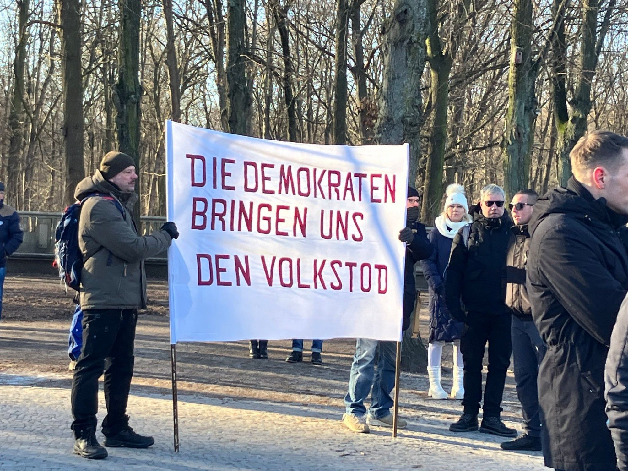 Demonstrierende mit Banner: Die Demokraten bringen uns den Volkstod