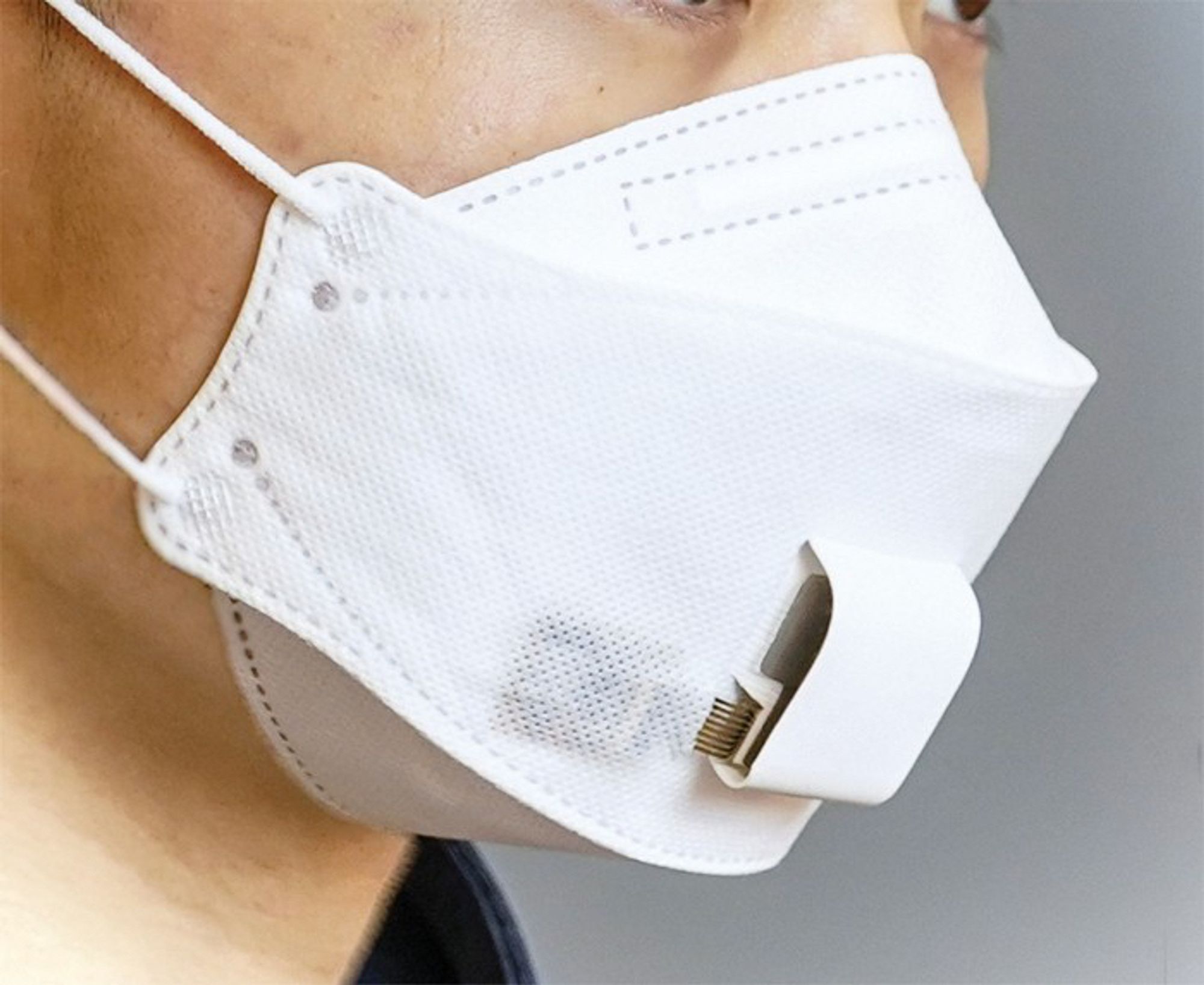 A person wearing a mask that includes a device that can analyze breath in real time.