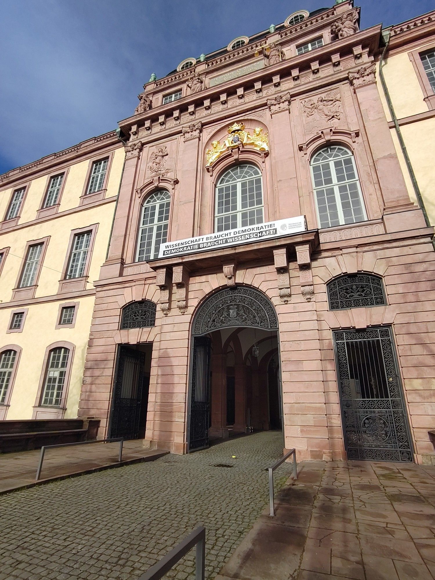 Eingangsportal des Residenzschloss Darmstadt mit dem Banner "Wissenschaft braucht Demokratie. Demokratie braucht Wissenschaft"