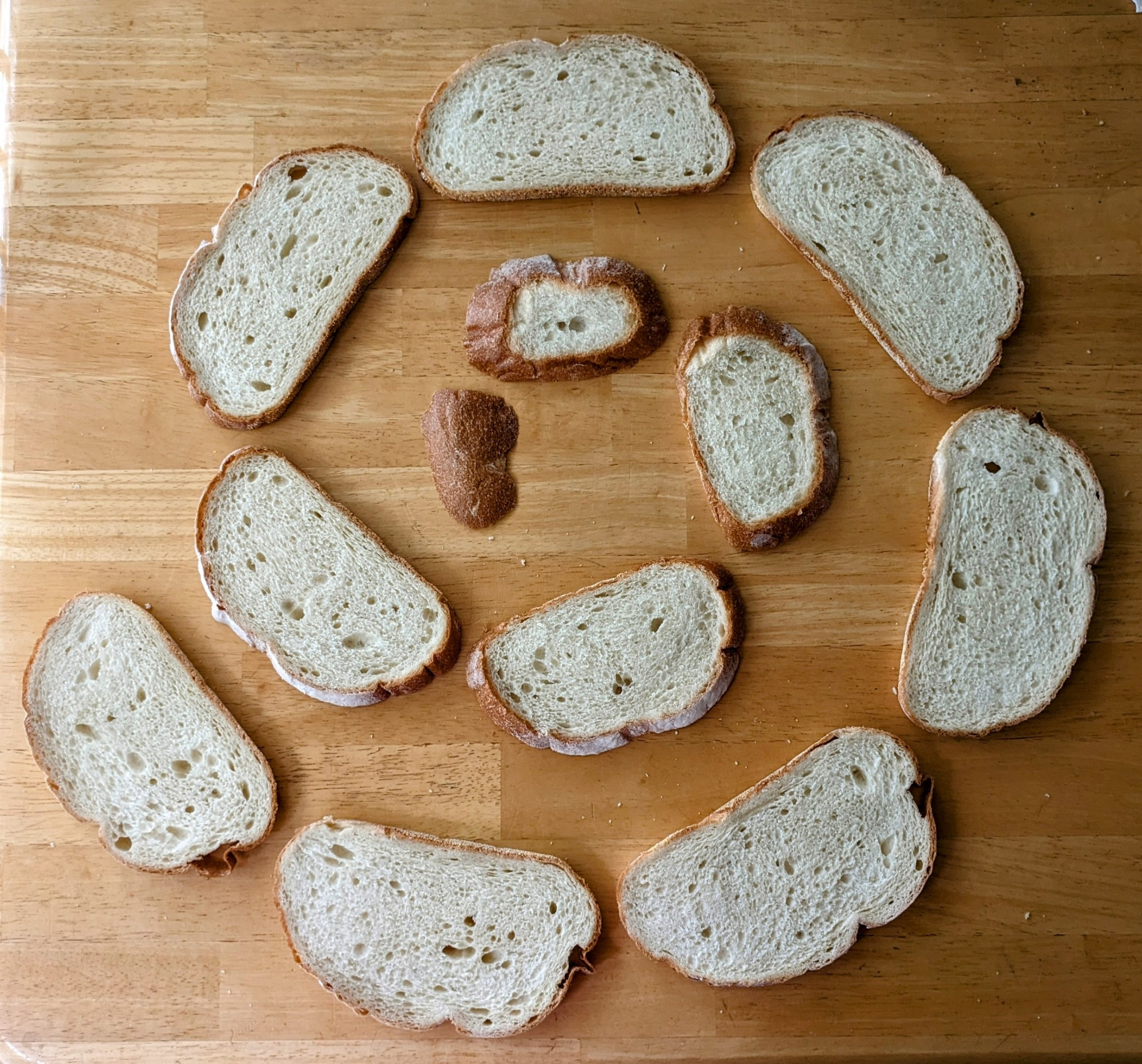 A spiral of bread slices on a wood table.