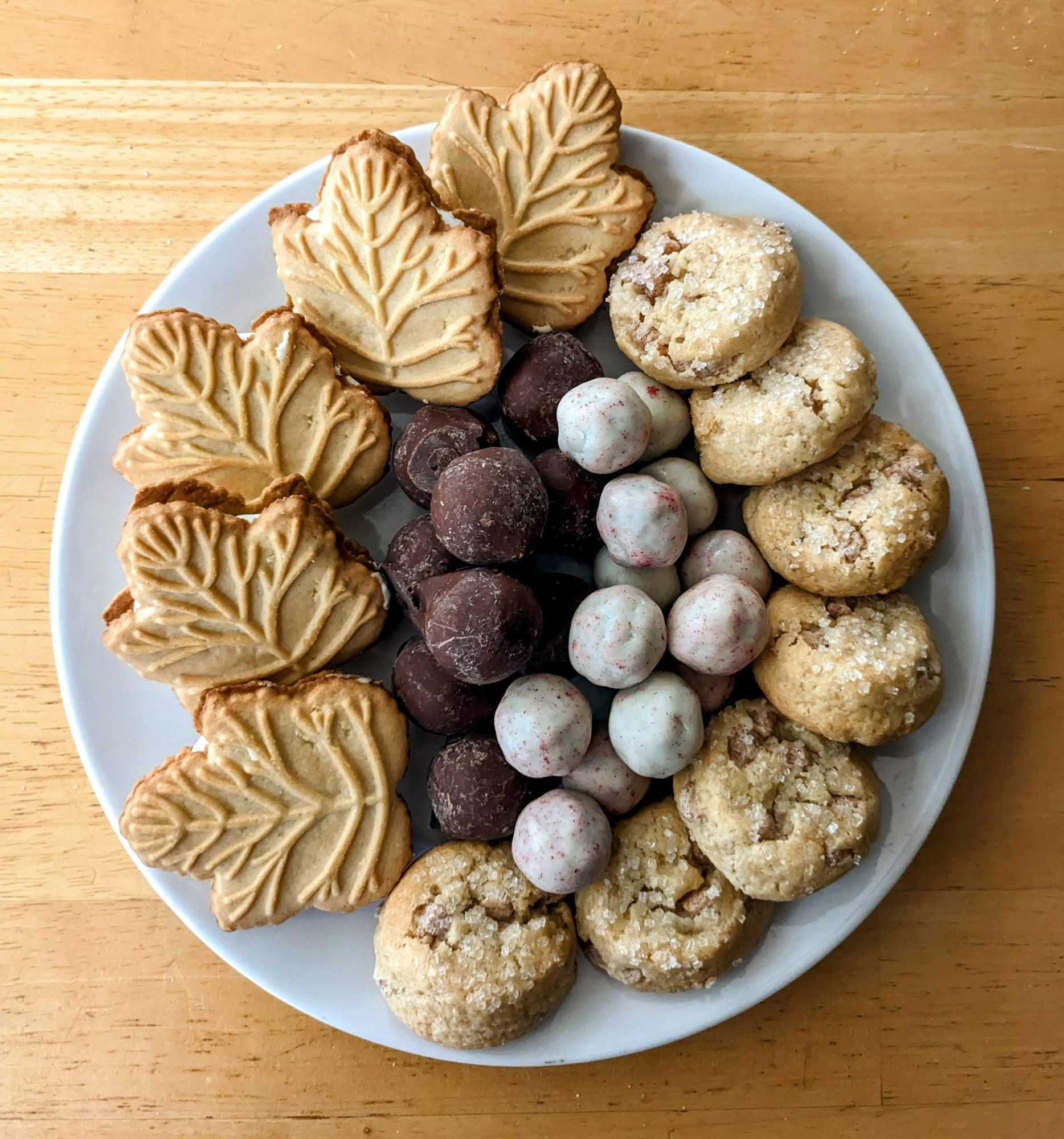 A white plate with an assortment of cookies and chocolate truffles.