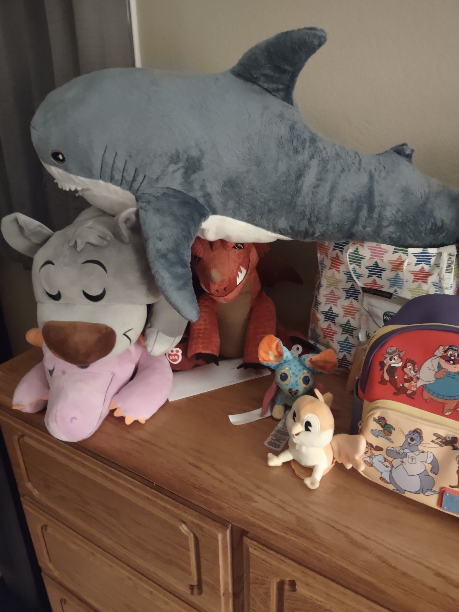 Picture of a pile of stuffed animals, Figment, Baloo, Dungeons & Dragons Red Dragon, IKEA Shark plush, etc