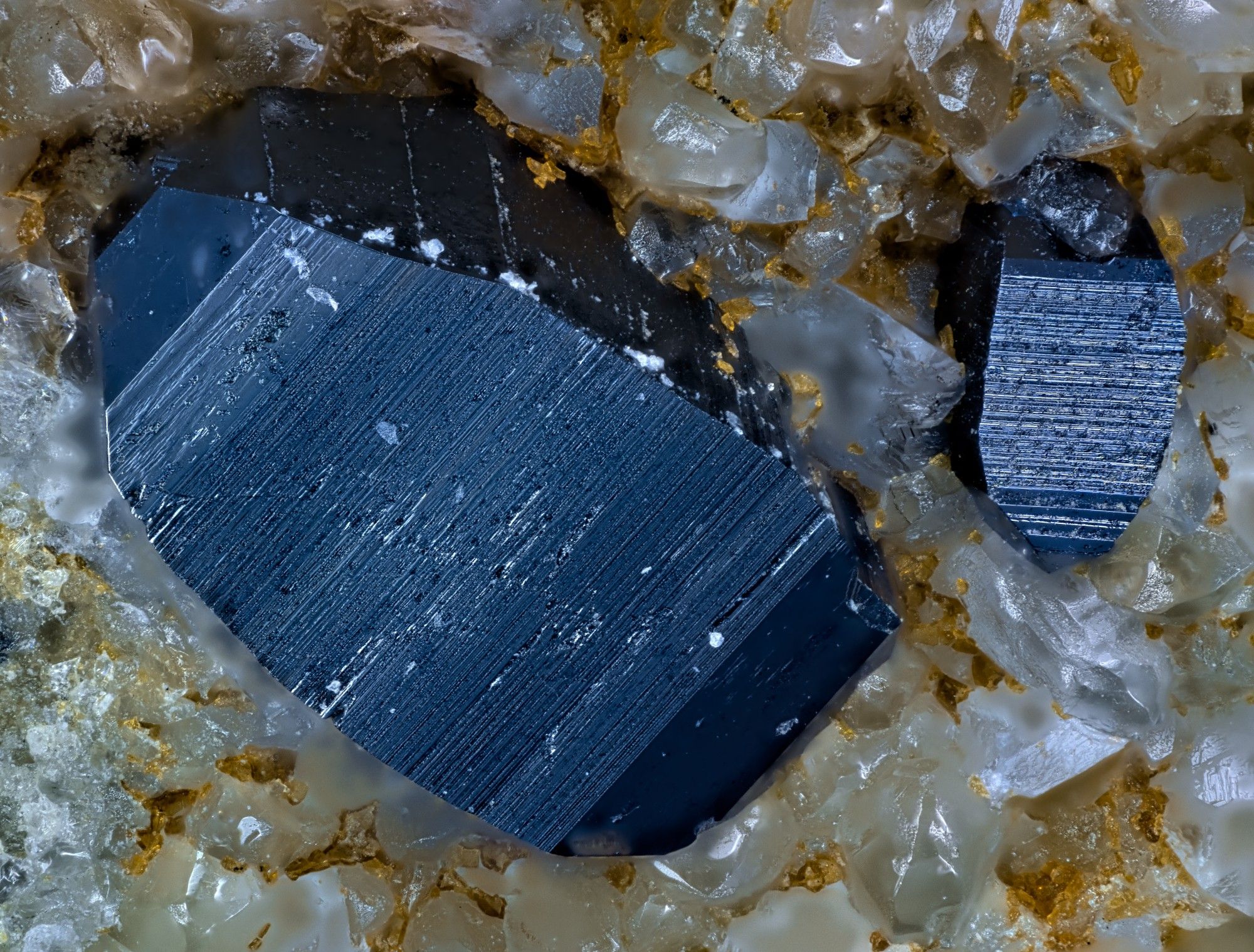 Large dark blue anatase crystal at left with a smaller crystal to right, both on a matrix of colorless quartz crystals.