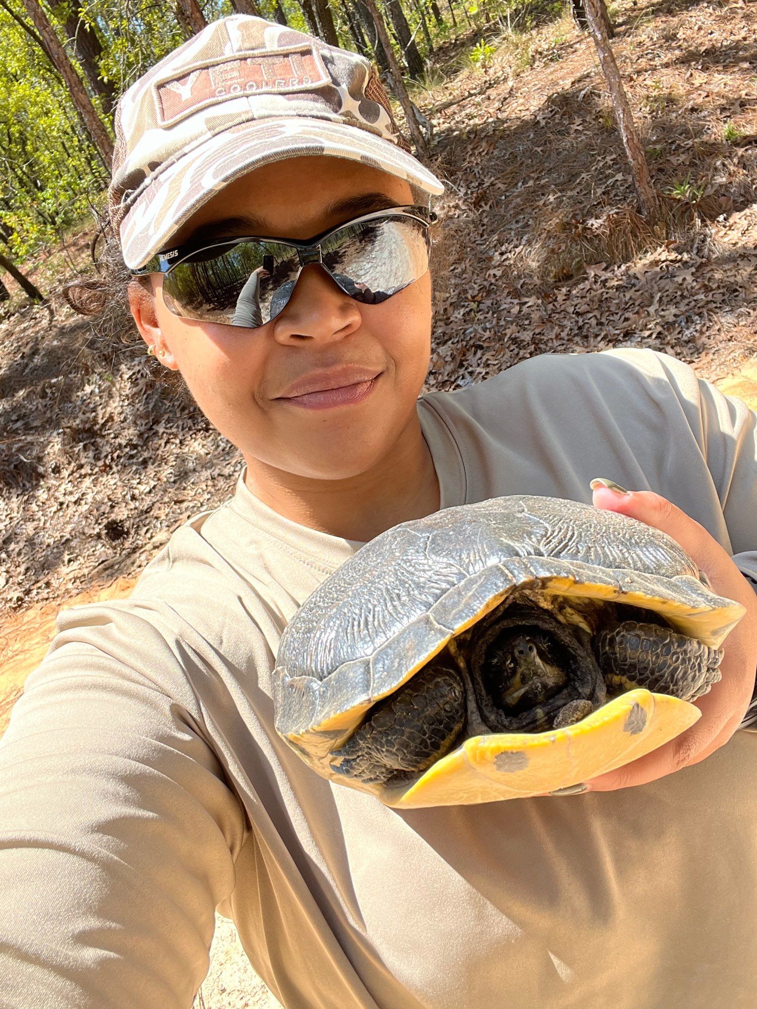 Lauren holds a yellow-bellied slider and smiles. 
