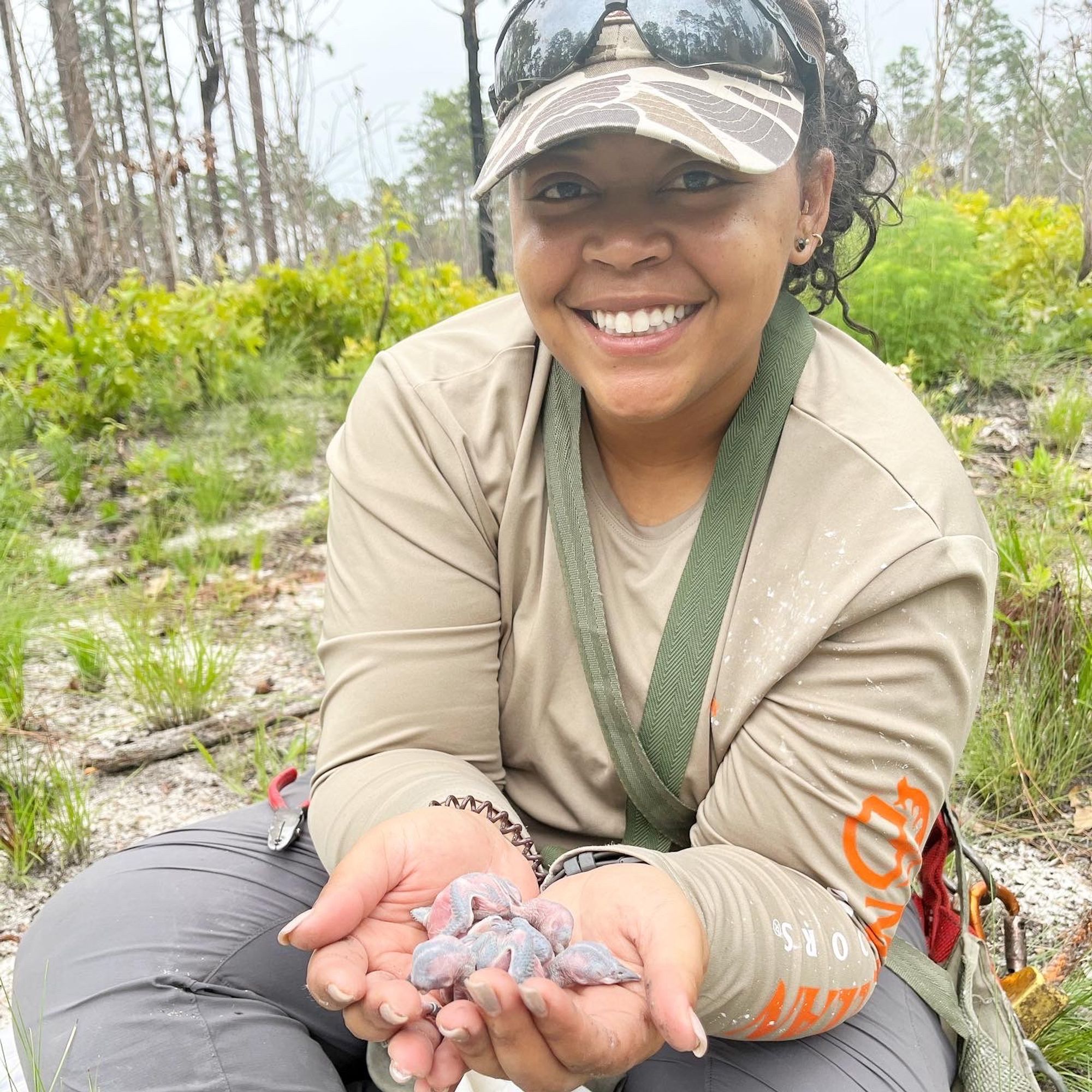 Lauren holds red cockaded woodpecker chicks and smiles. 