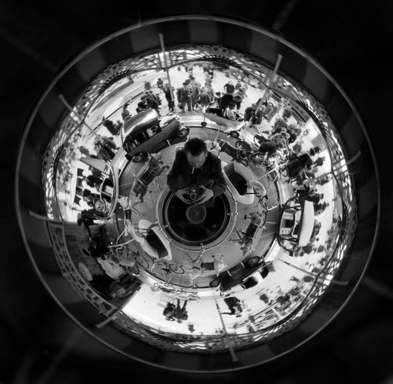 man and a merry go-round reflected in a circular mirror