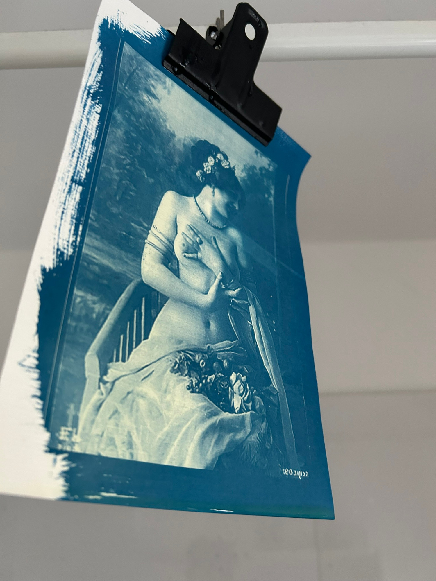 cyanotype on paper of a woman partially clothed. She has flowers in her hair