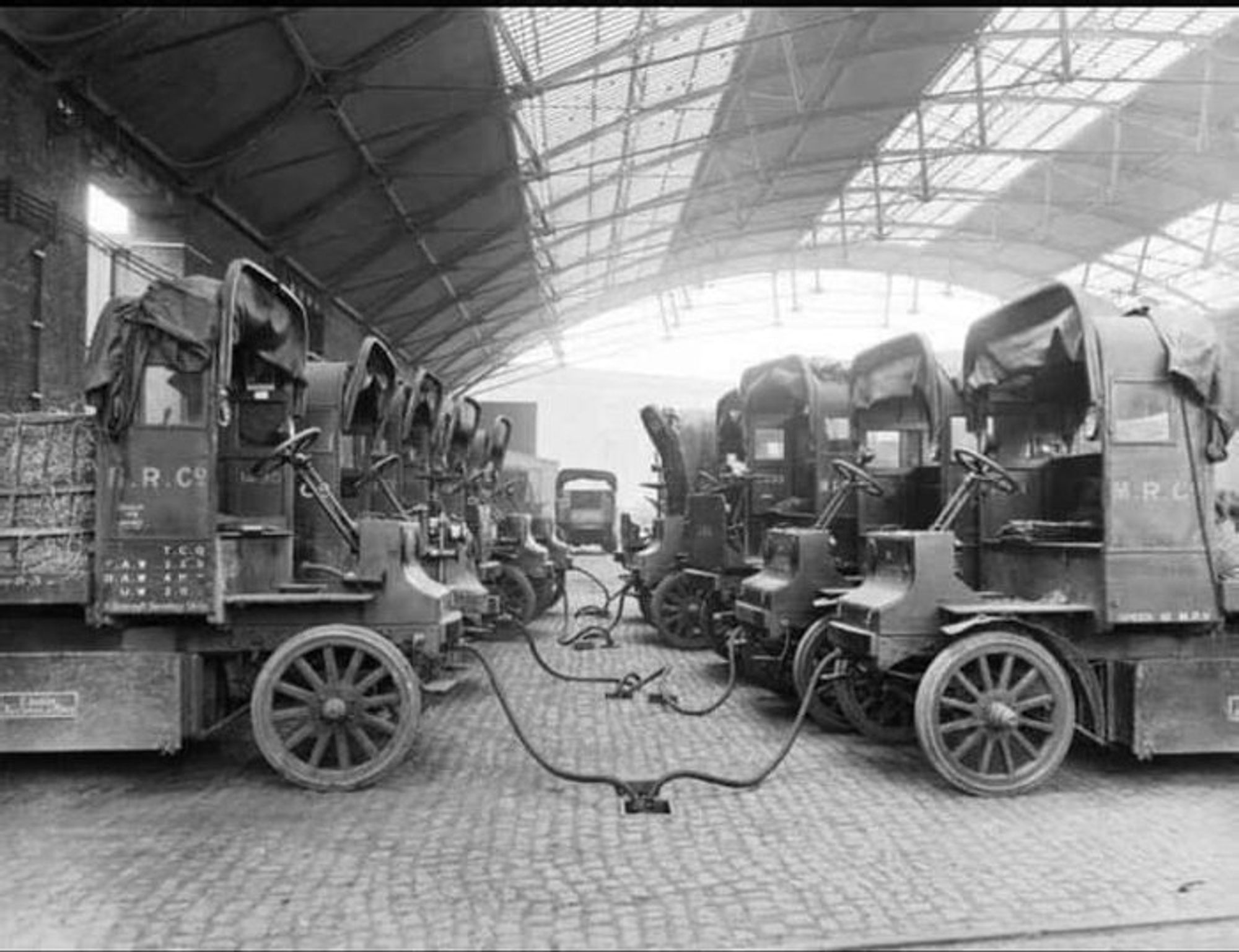 photo
two rows of parked vehicles that are all plugged into cables emerging from the cobbled floor