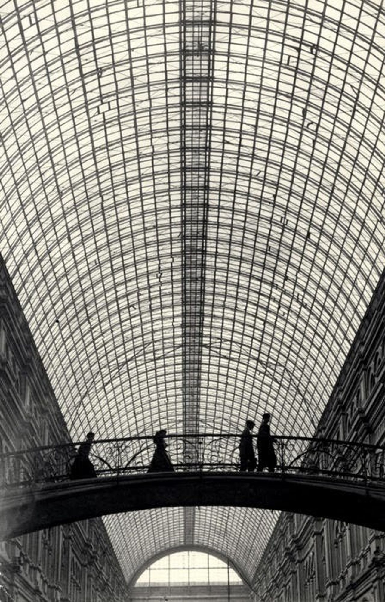 photo
under a vast glass ceiling 4 figures are crossing an elevated bridge