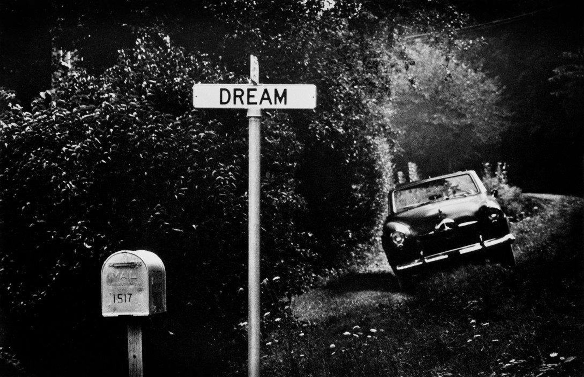 photo
a sign reading dream
a mail box with 15117 stenciled on it
and a parked car on a verdant verge