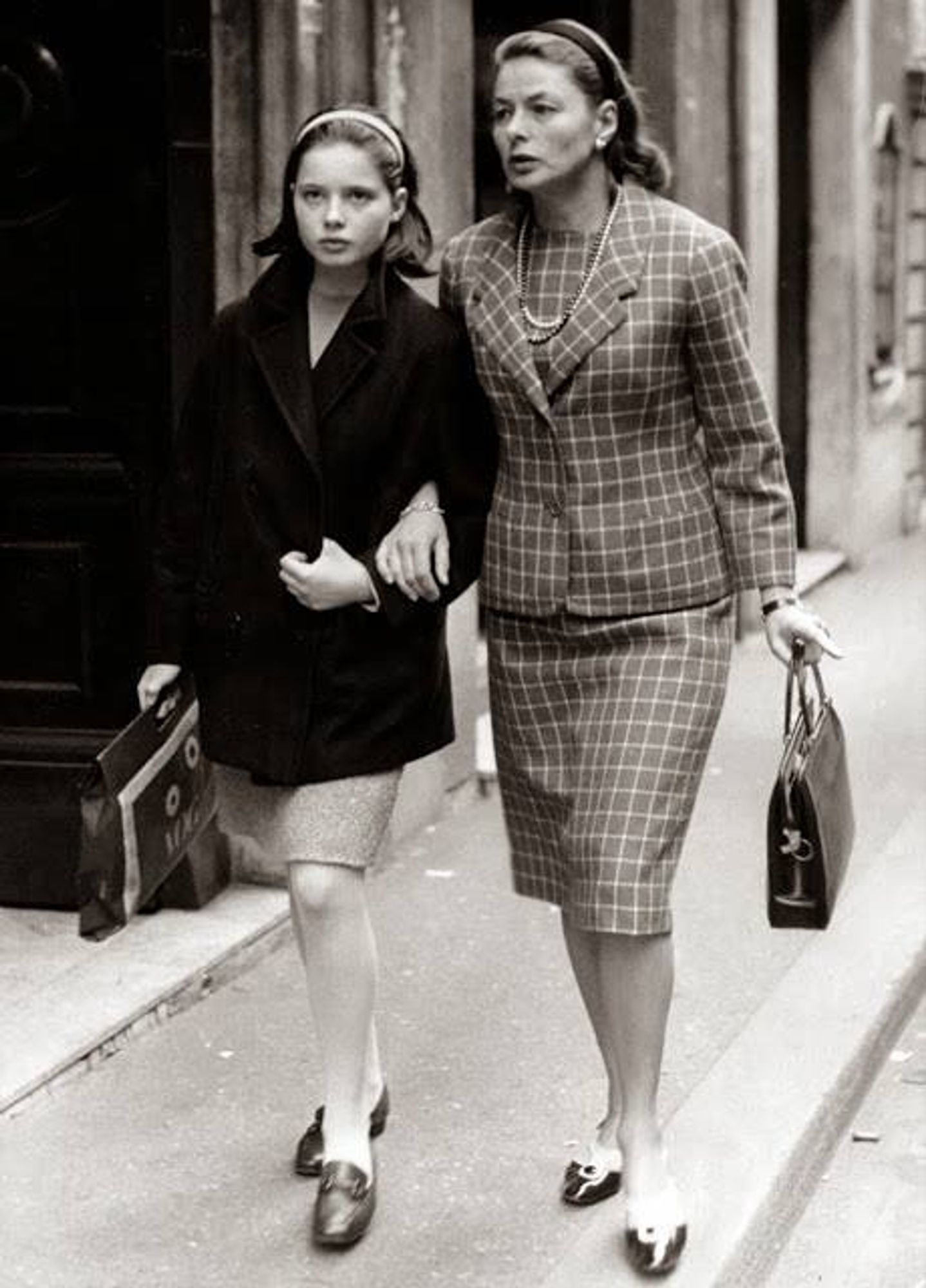 Ingrid is on the right, wearing a square patterned outfit
both are carrying handbags