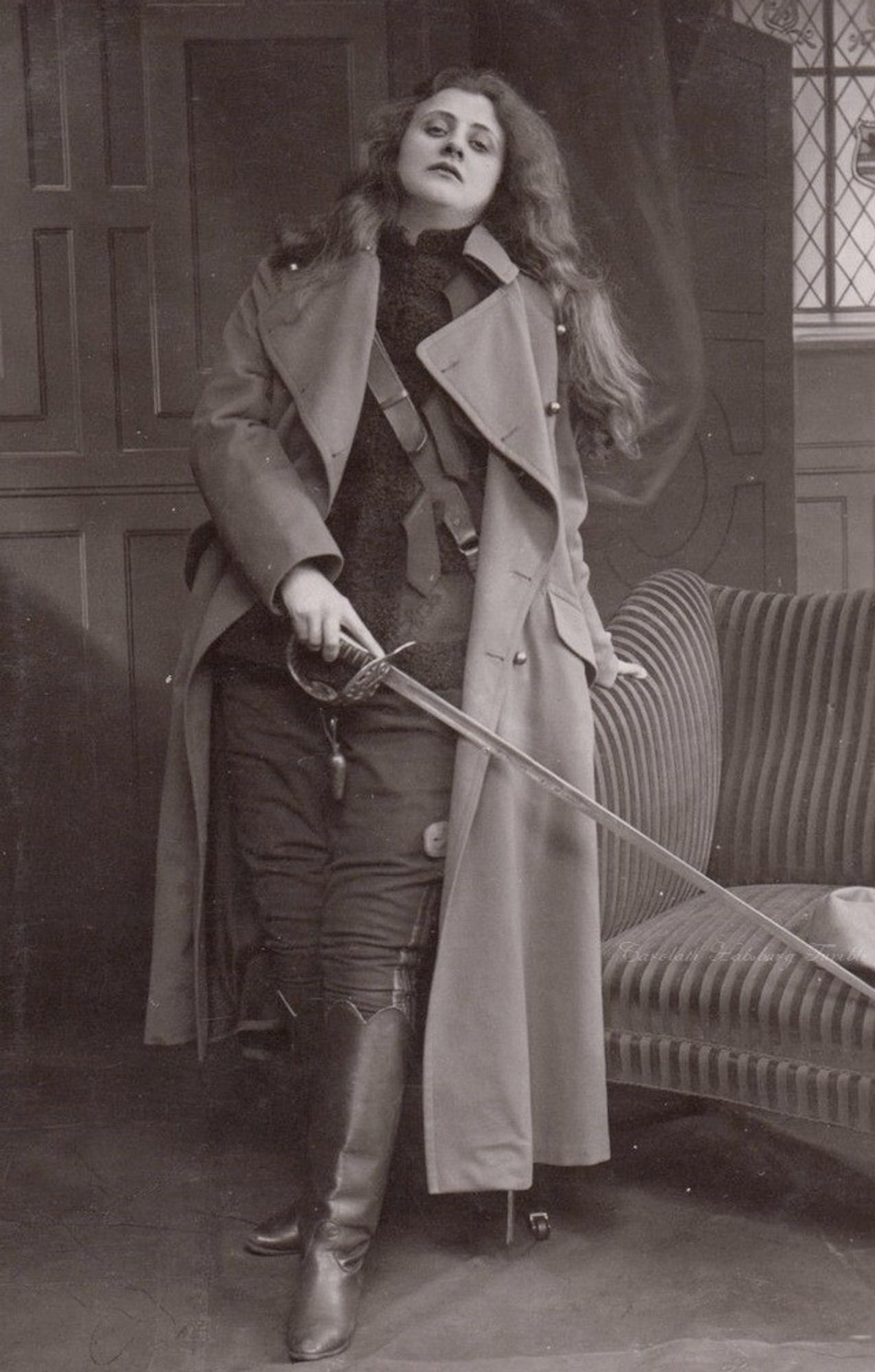 woman in a soliders uniform and long coat, she is holding a sword