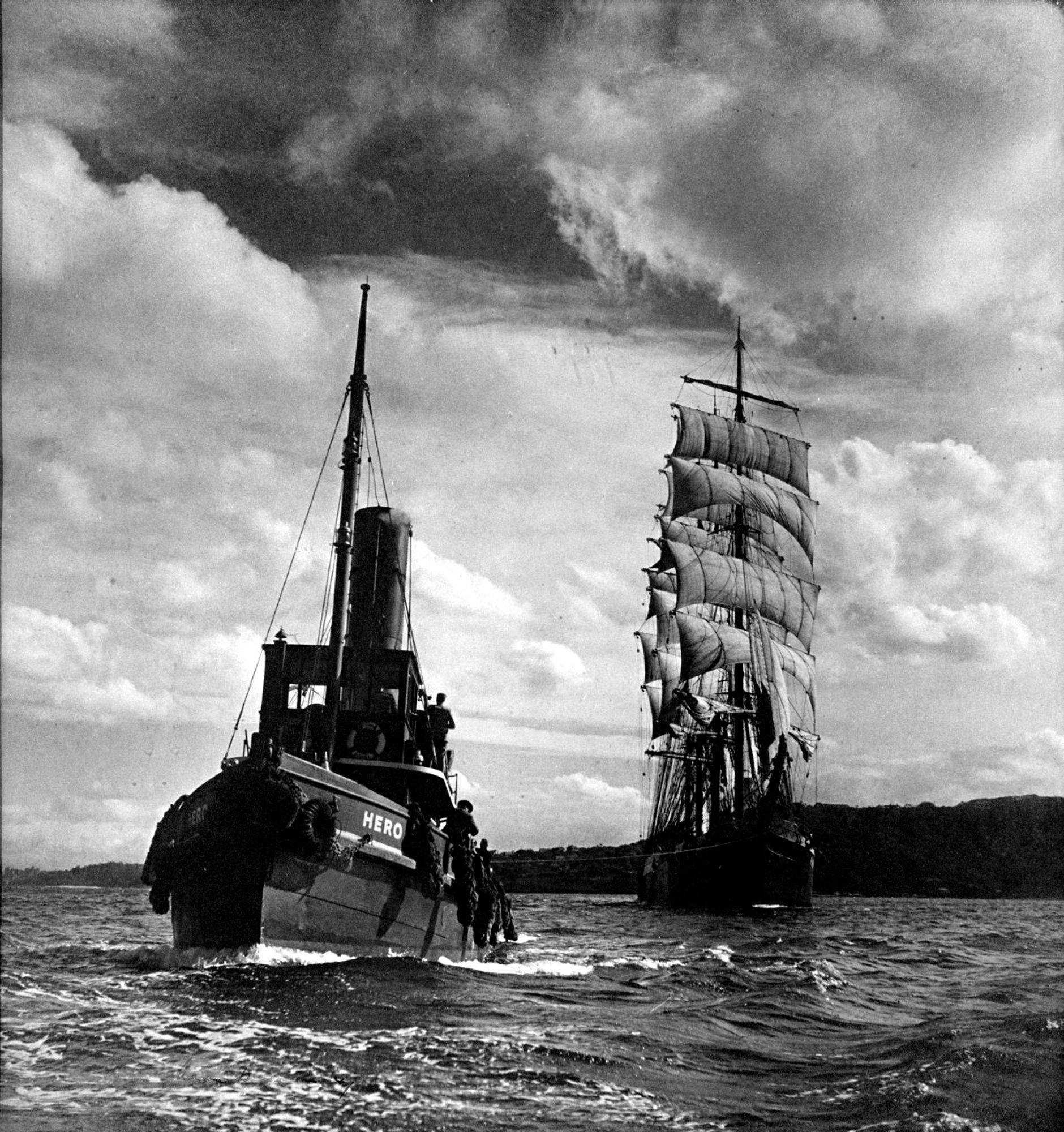 photo
a tug towing a sailing ship. The ship is under full sail.
a stormy sky looms