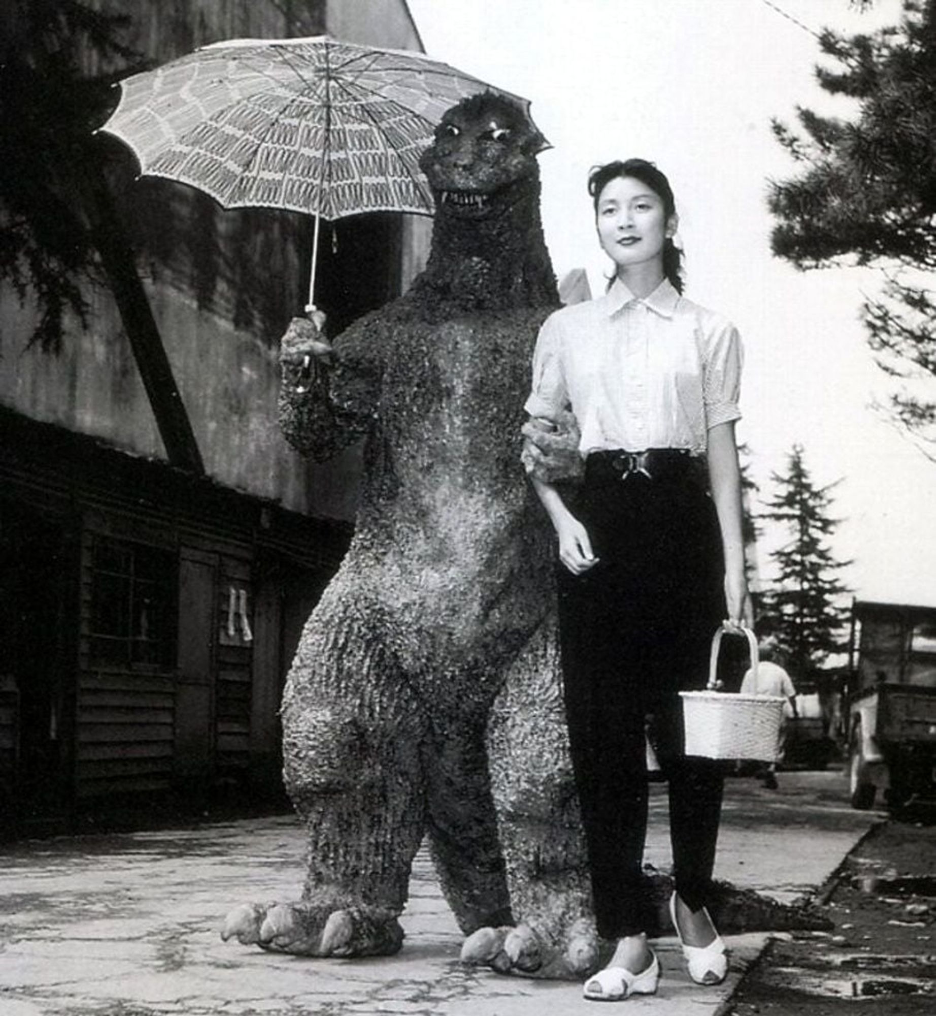 Godzilla holding an umbrella promenading with a young woman,