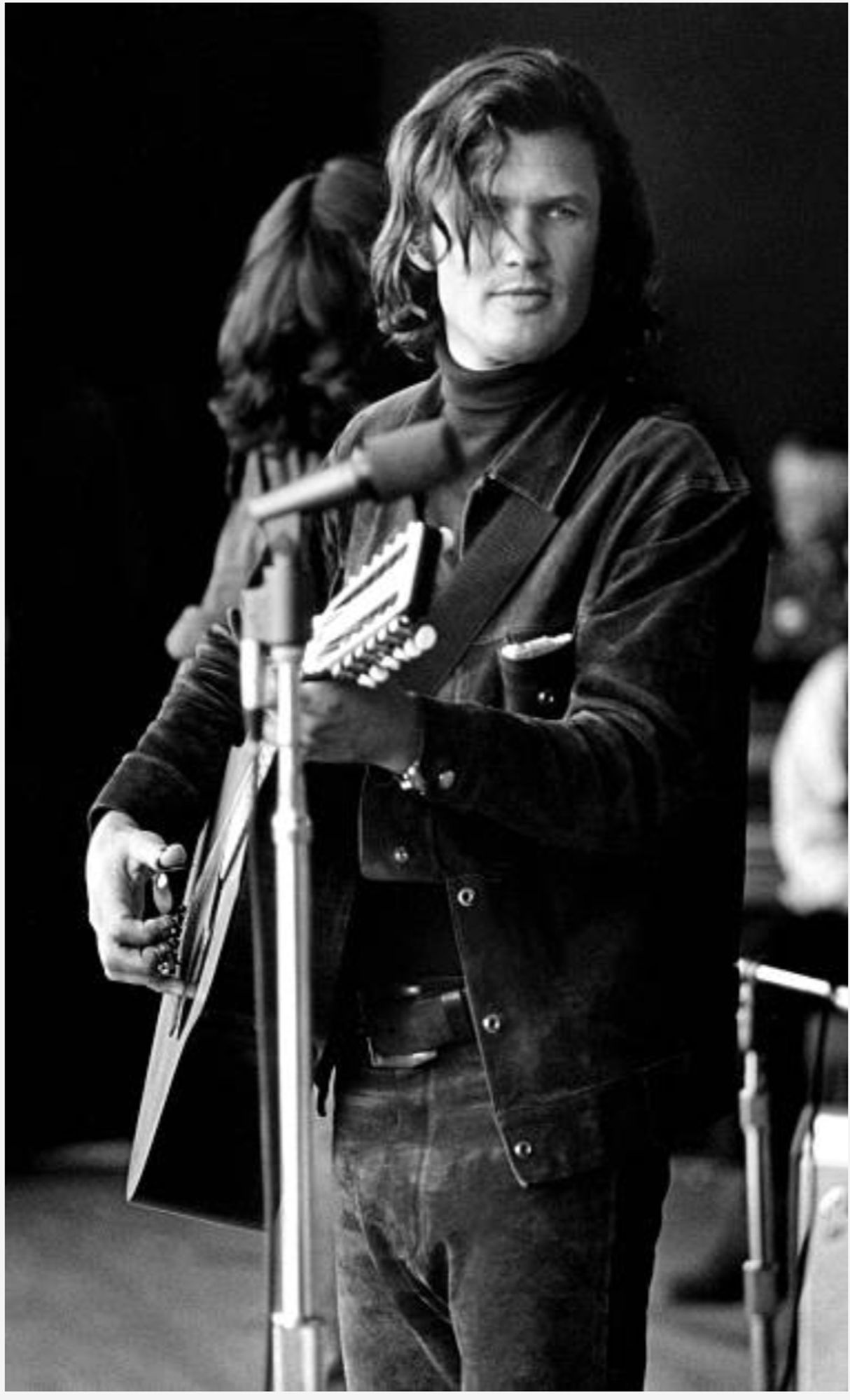 Kristofferson stands at a microphone with his 12-string guitar