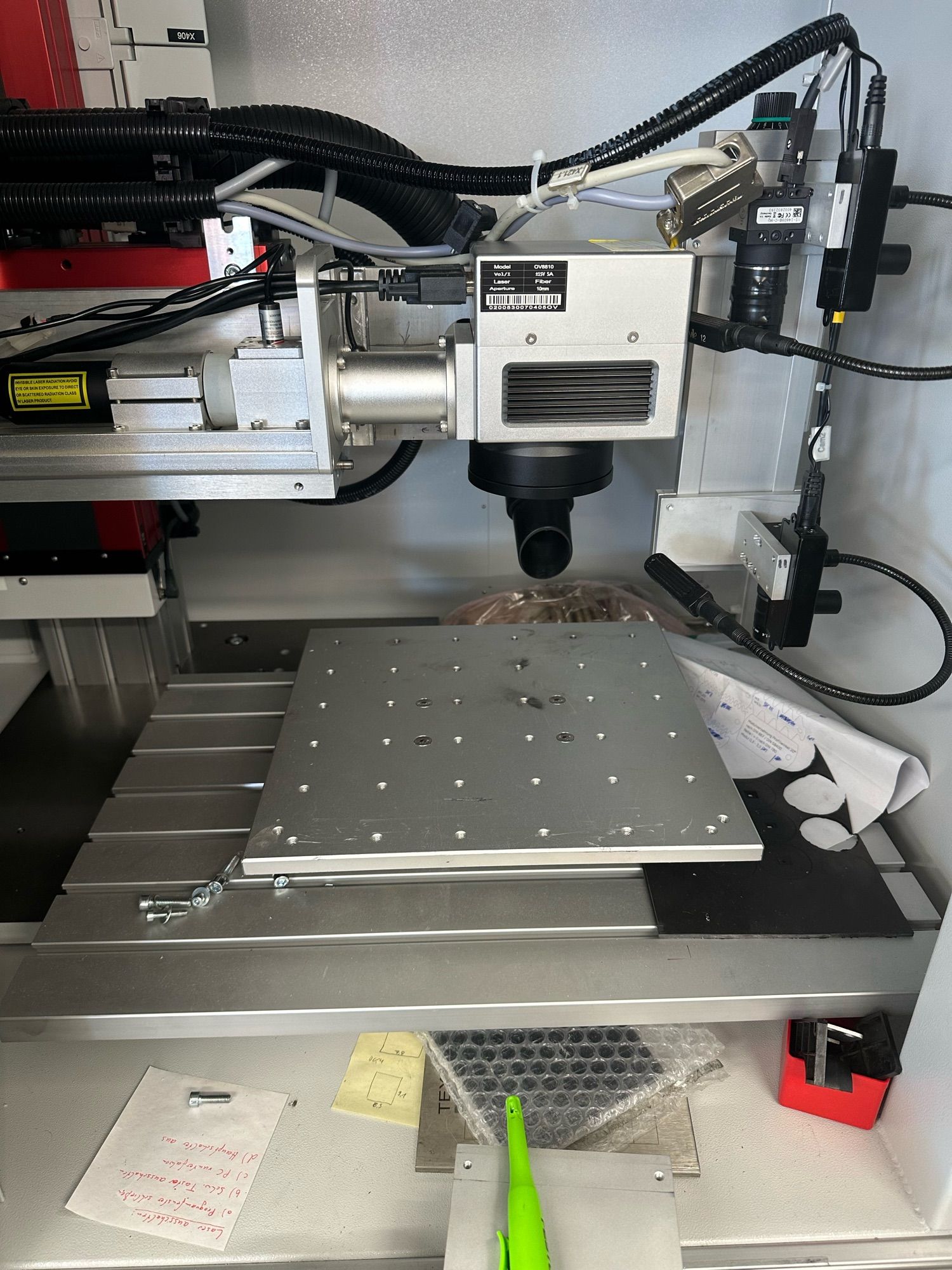 A wider angle view of the two cameras and the laser scanning head over the table with the screw hole grid on it.