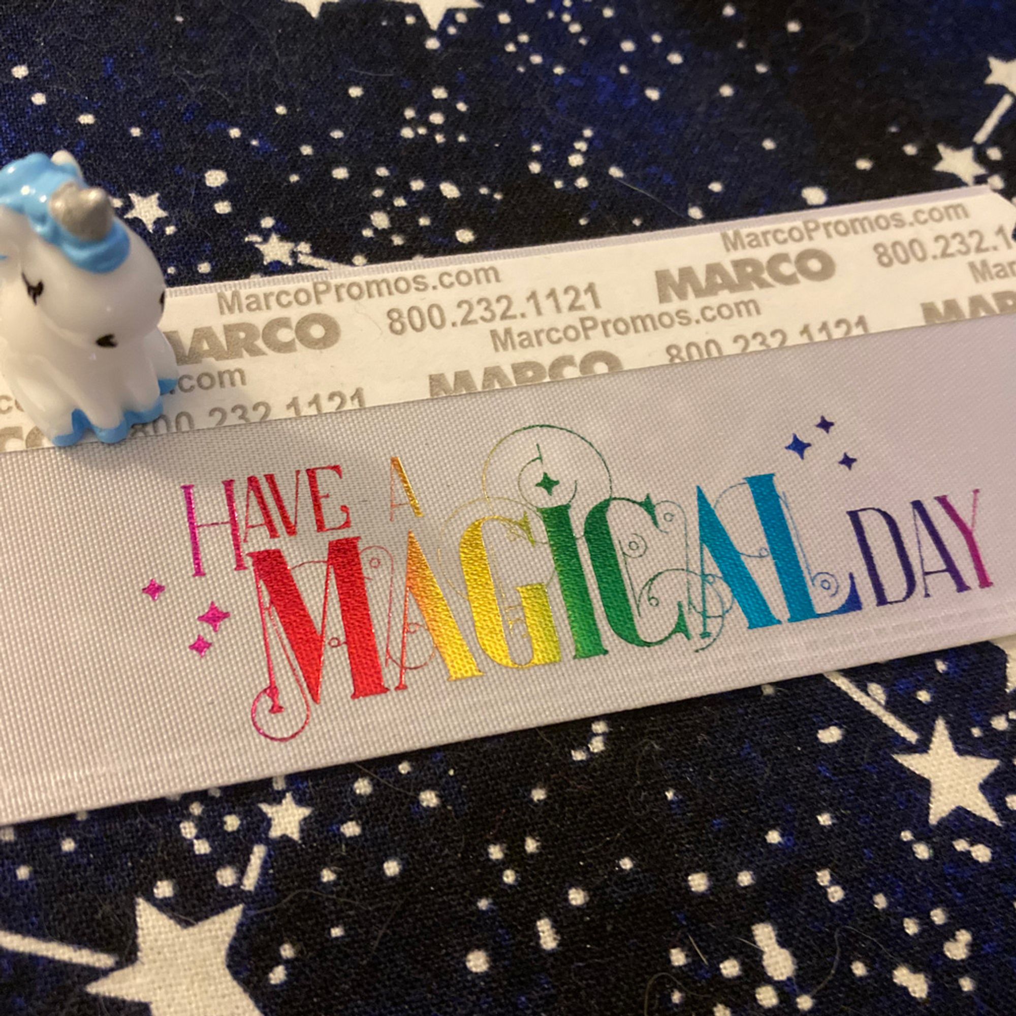 A little resin unicorn on a badge ribbon that says "Have a Magical Day".