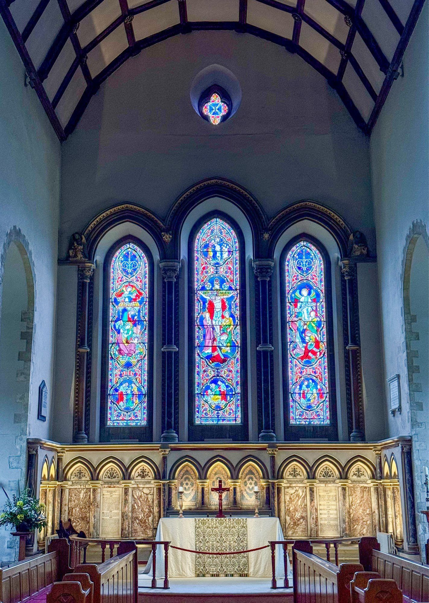 A photo of stained glass window windows behind the altar in a church