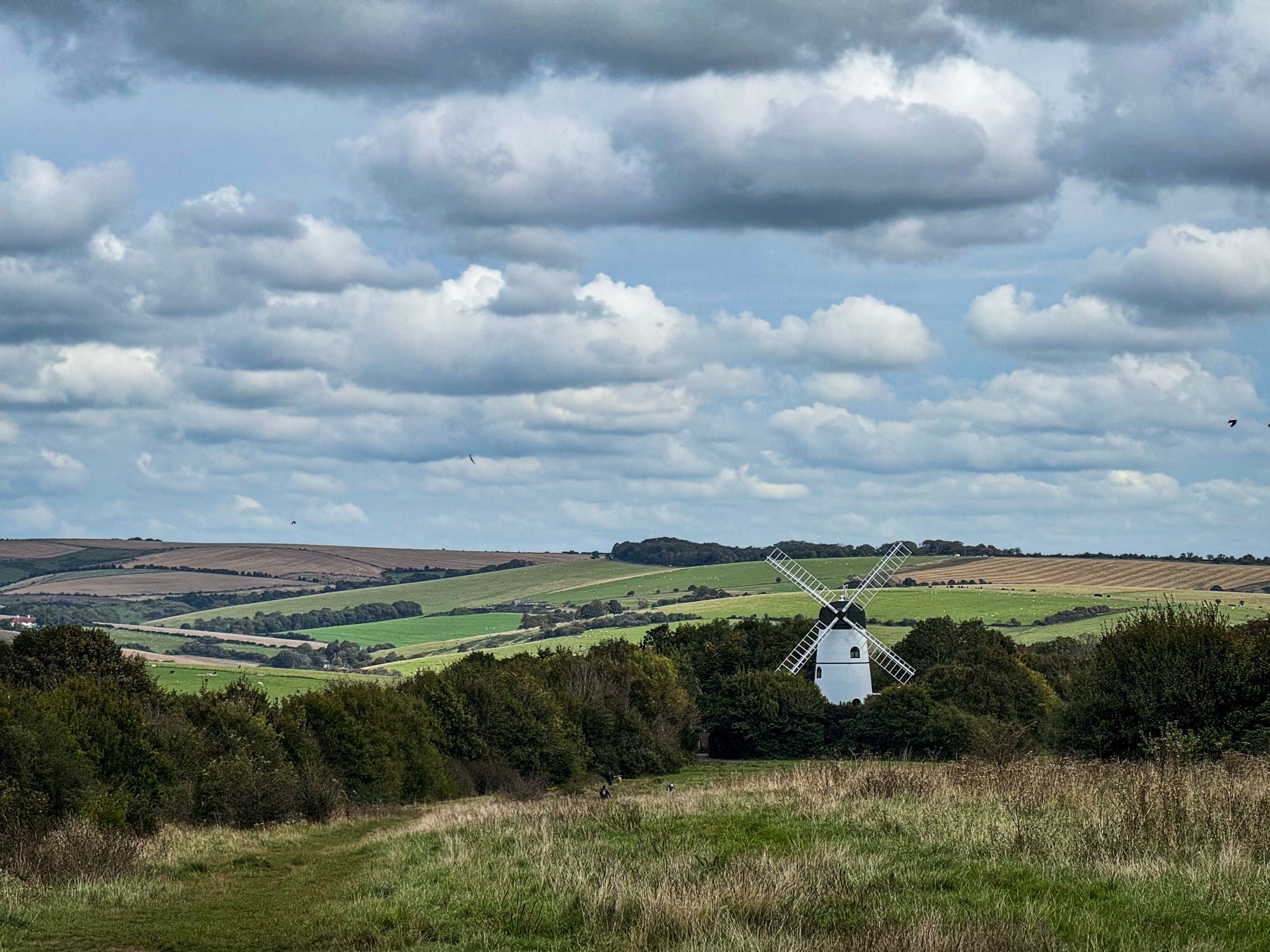 A windmill set in the South Downs with lots of clouds.