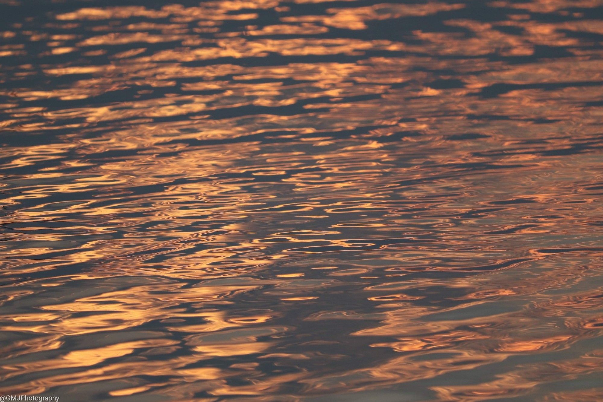 Peachy colored light reflects off endless repeating watery ripples.