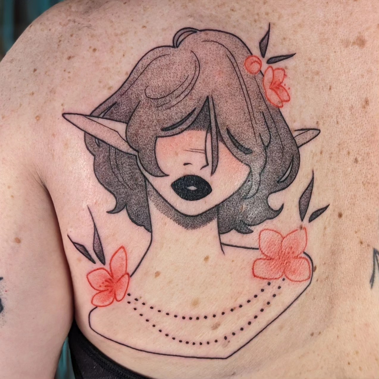 A large black & grey back tattoo of a mysterious elf with a neutral expression. Short, shag cut hair covers her eyes. Red flowers sit on her shoulders and hair.