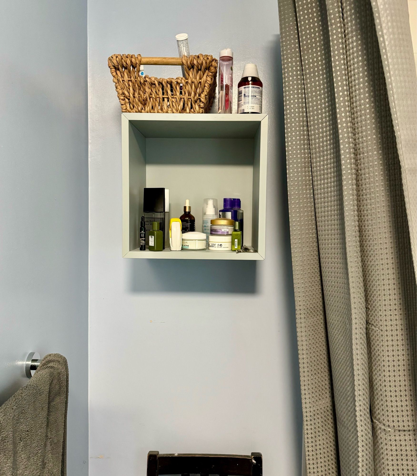 The corner of my bathroom now has a grey/green open cubed shelve with toiletries on it. There’s a grey shower curtain to the right and a grey towel on a rail to the right