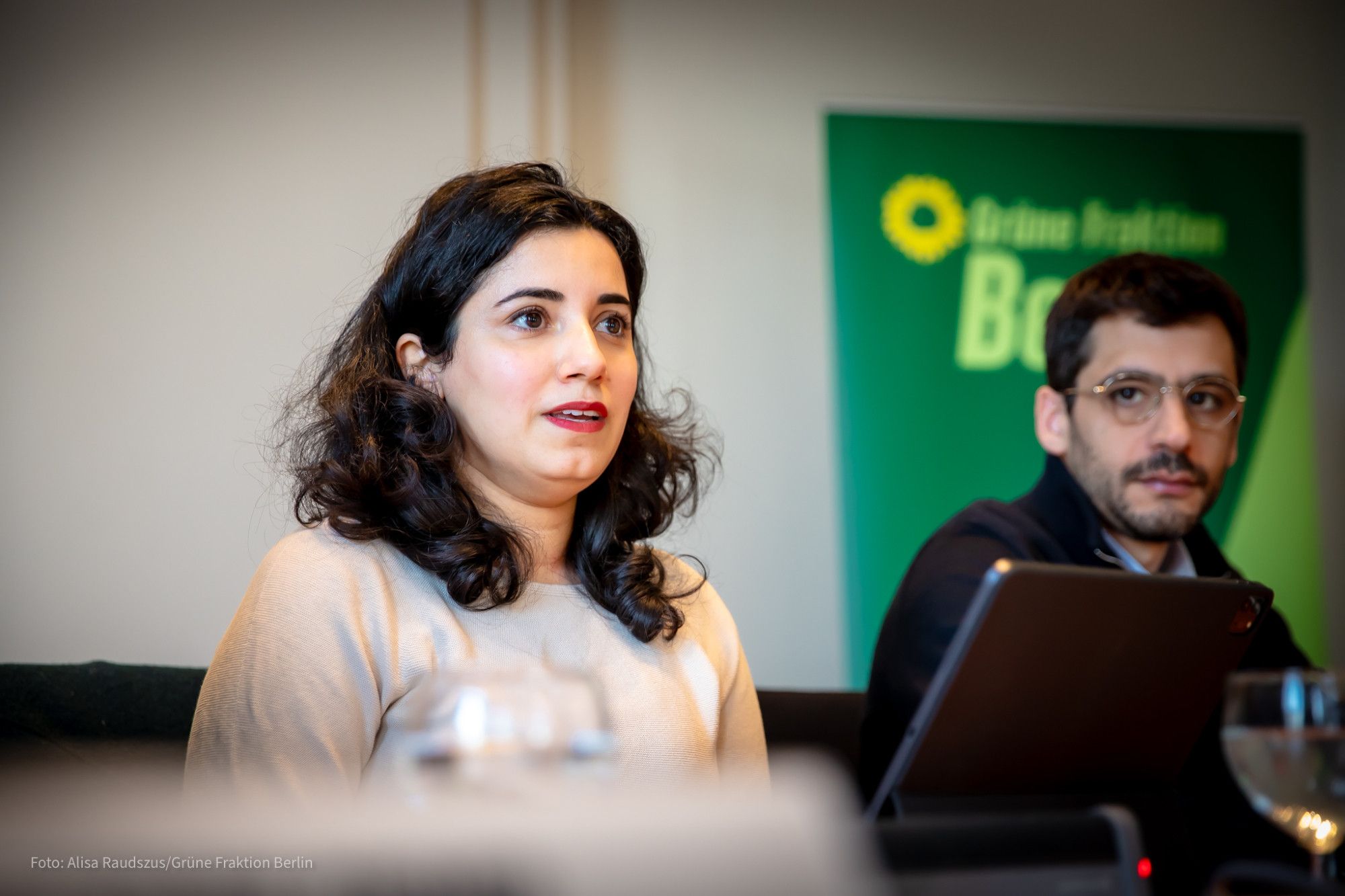 Misbah Khan sitzt an einem Tisch und spricht, neben ihr sitzt Ario Mirzaie. Sie ist eine junge Frau mit langen dunklen Locken.