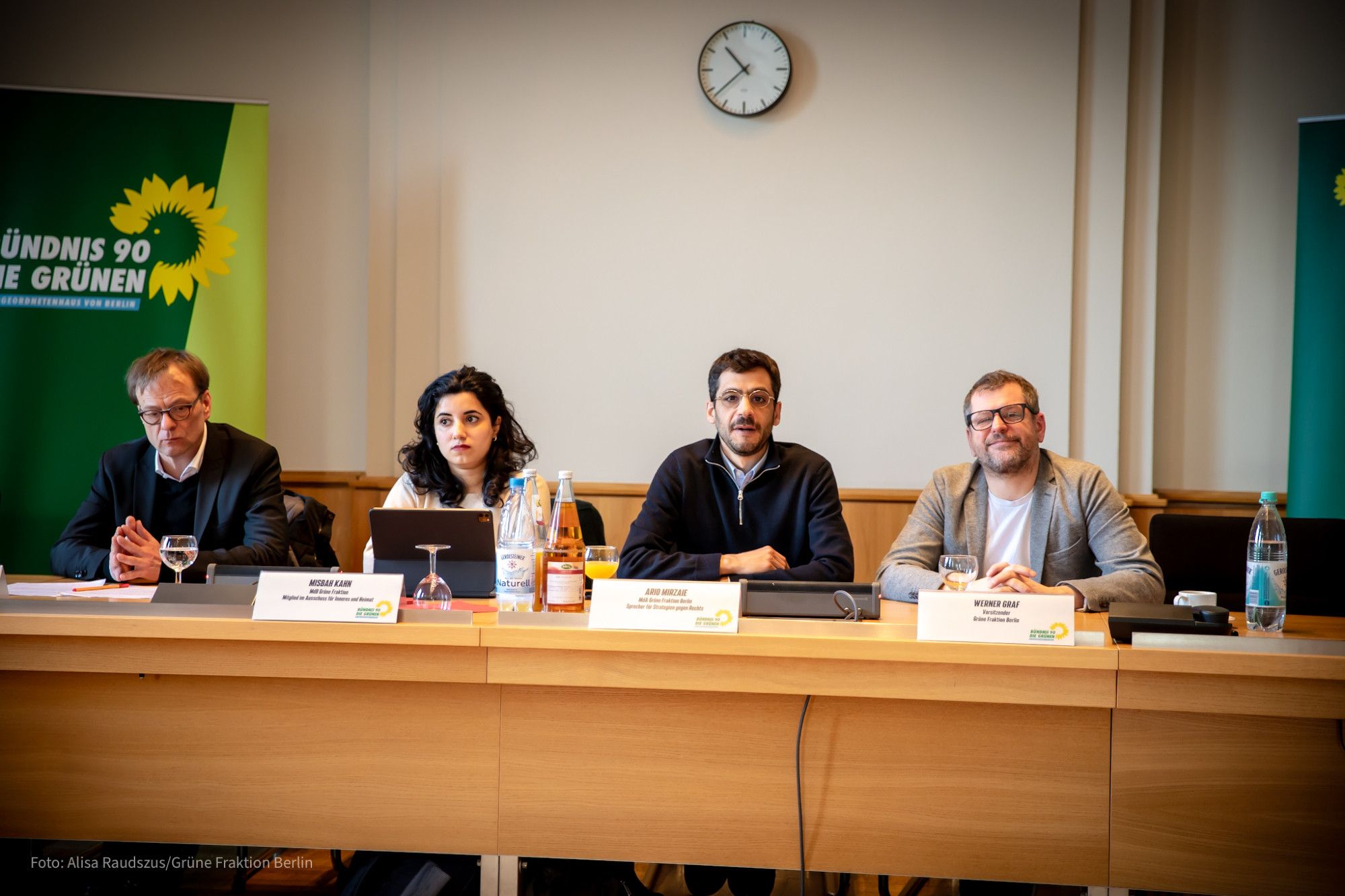 Gruppenfoto von 4 Personen die nebeneinander an einem Tisch sitzen wie bei einer Pressekonferenz. Von links nach rechts: Dr. Hendrik Cremer, Misbah Khan, Ario Mirzaie und Werner Graf. Hinter ihnen sieht man grüne Banner.