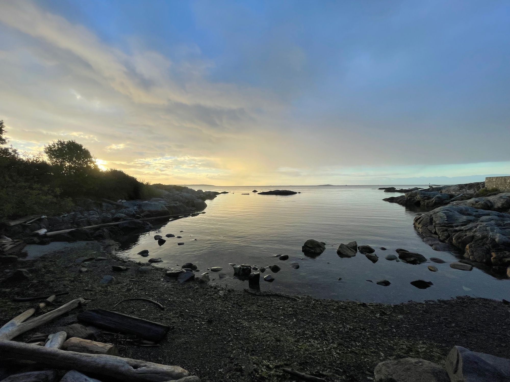 A small rocky cove reflects the early, “just after sunrise” sky.