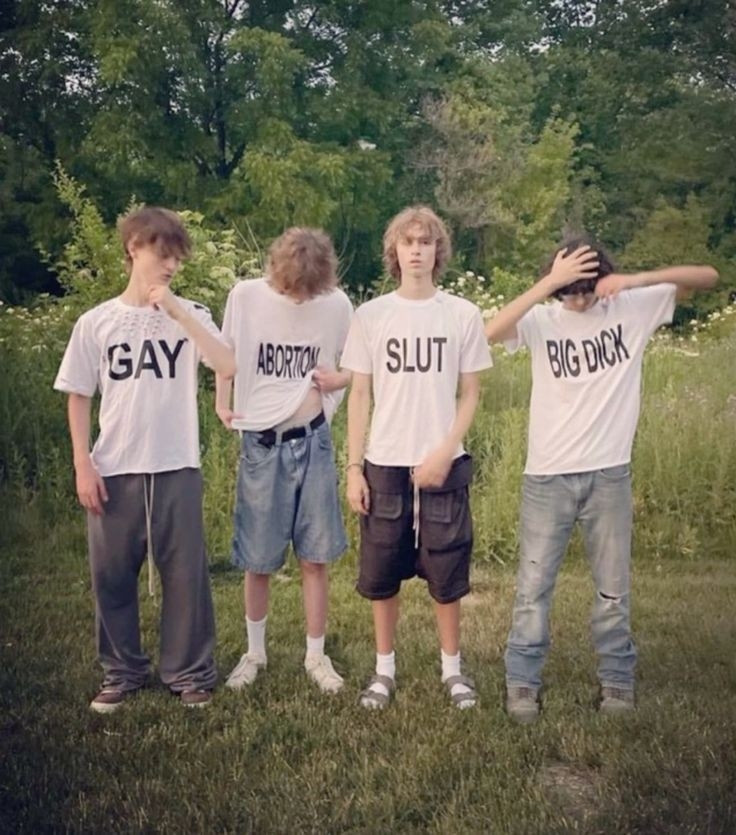 Four white men standing in a line with white tee shirts with bold all caps black text words. Each shirt has a different word. Starting with the person on the left his shirt says "GAY" the next person in line has a shirt that says "ABORTION" the next person in line has a shirt that says "SLUT" the last person in the line has a shirt that says "BIG DICK"