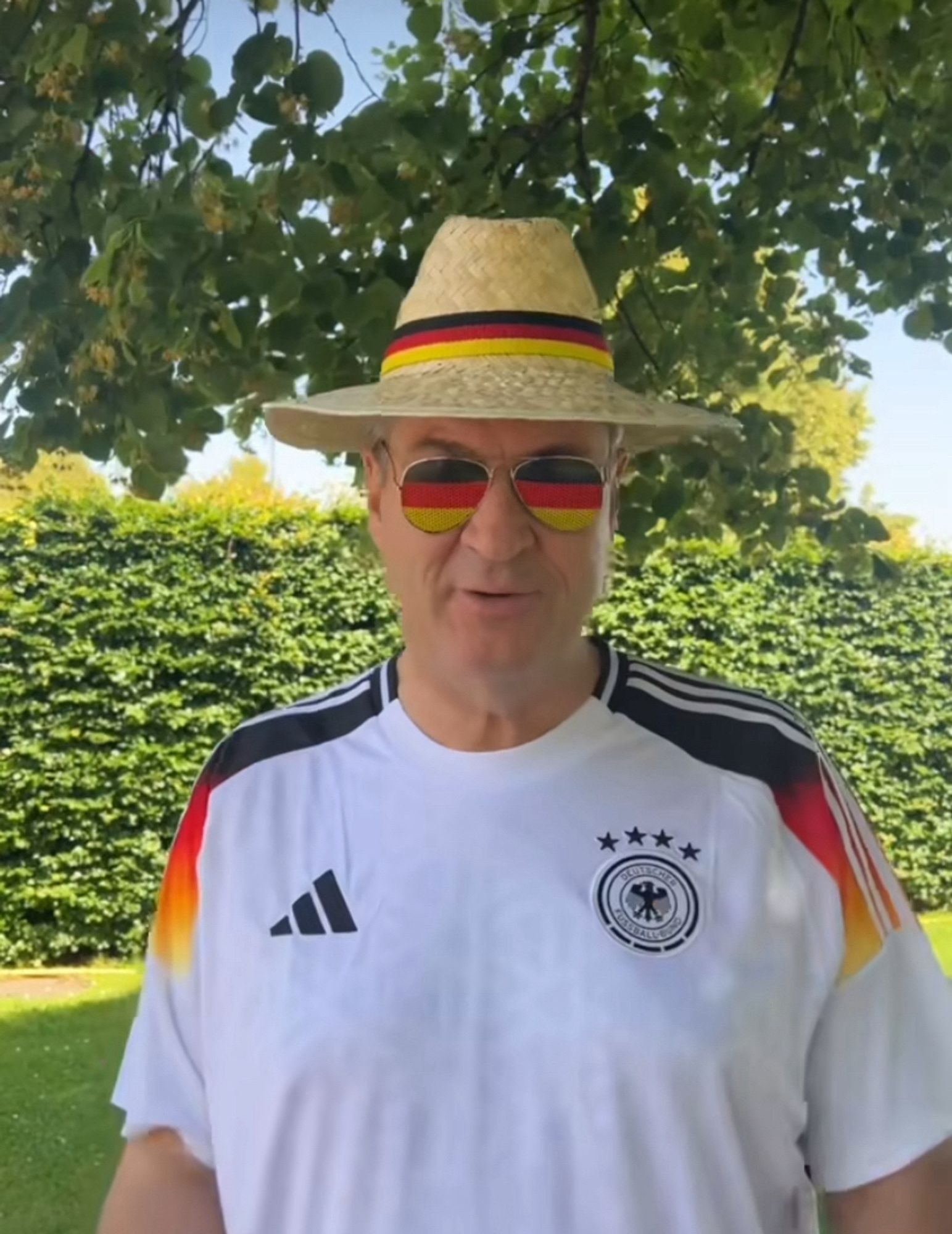 Söder mit peinlicher Deutscjlandbrille, Trikot und strohhut