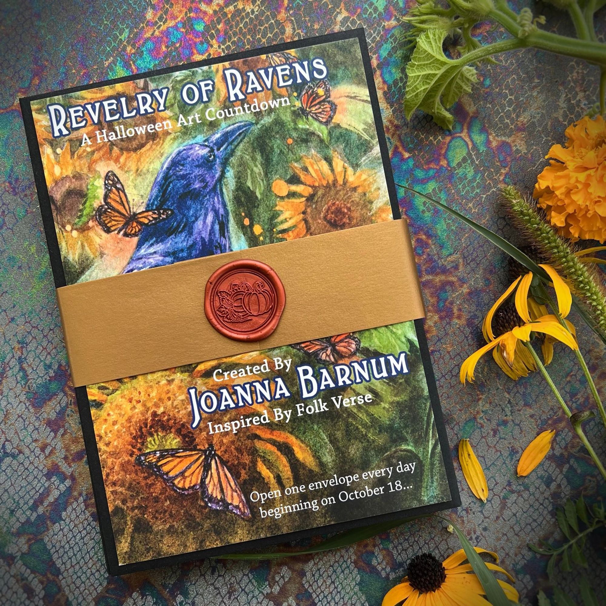 A photo of a "Halloween Art Countdown," a stack of envelopes with an illustrated cover, bundled together with a decorative band and wax seal. The cover says "Revelry of Ravens" with an illustration of a raven with sunflowers and butterflies.