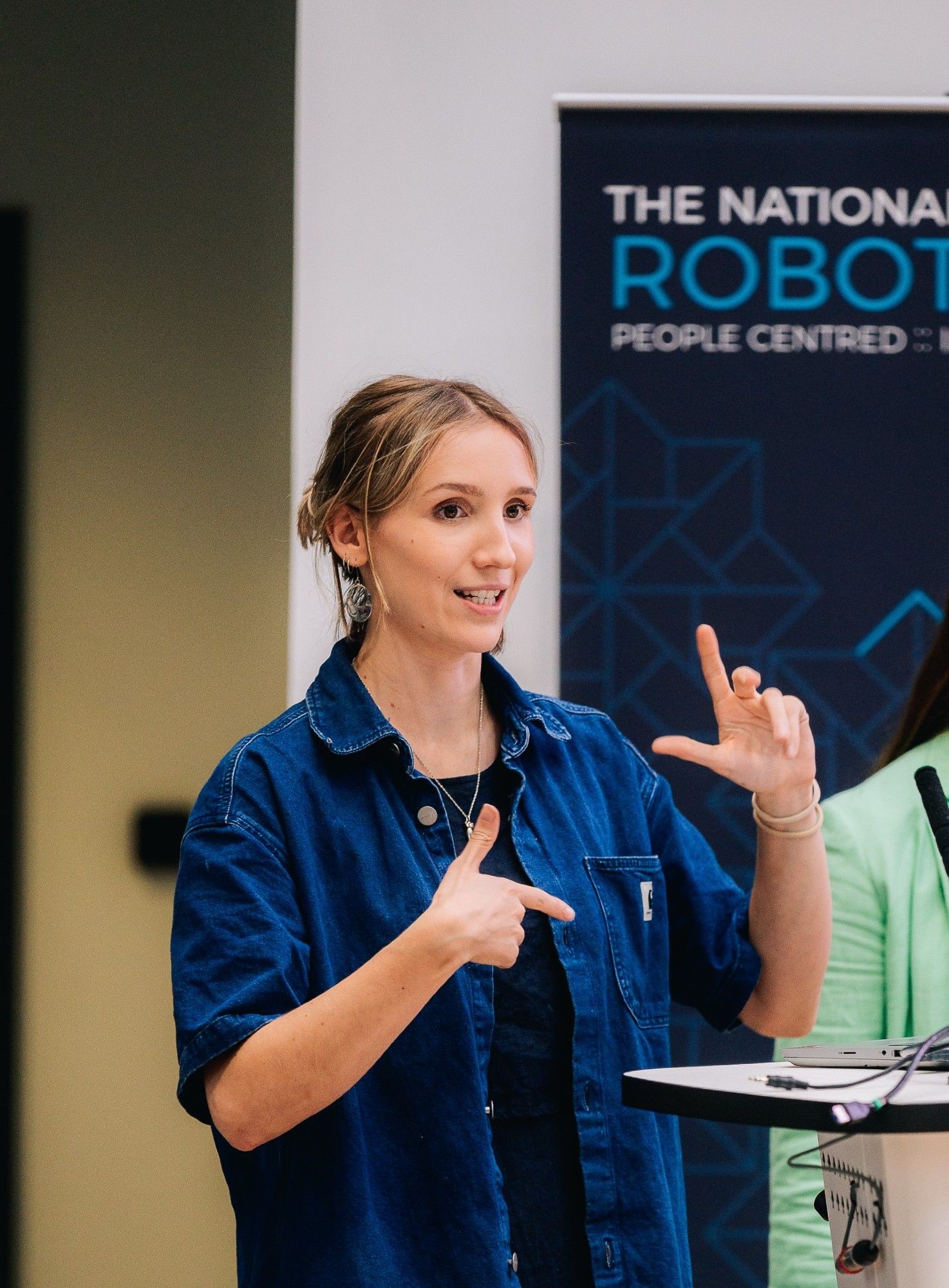 A picture of Isabelle speaking at the National Robotarium. She's wearing a dark blue denim shirt and a black t-shirt.