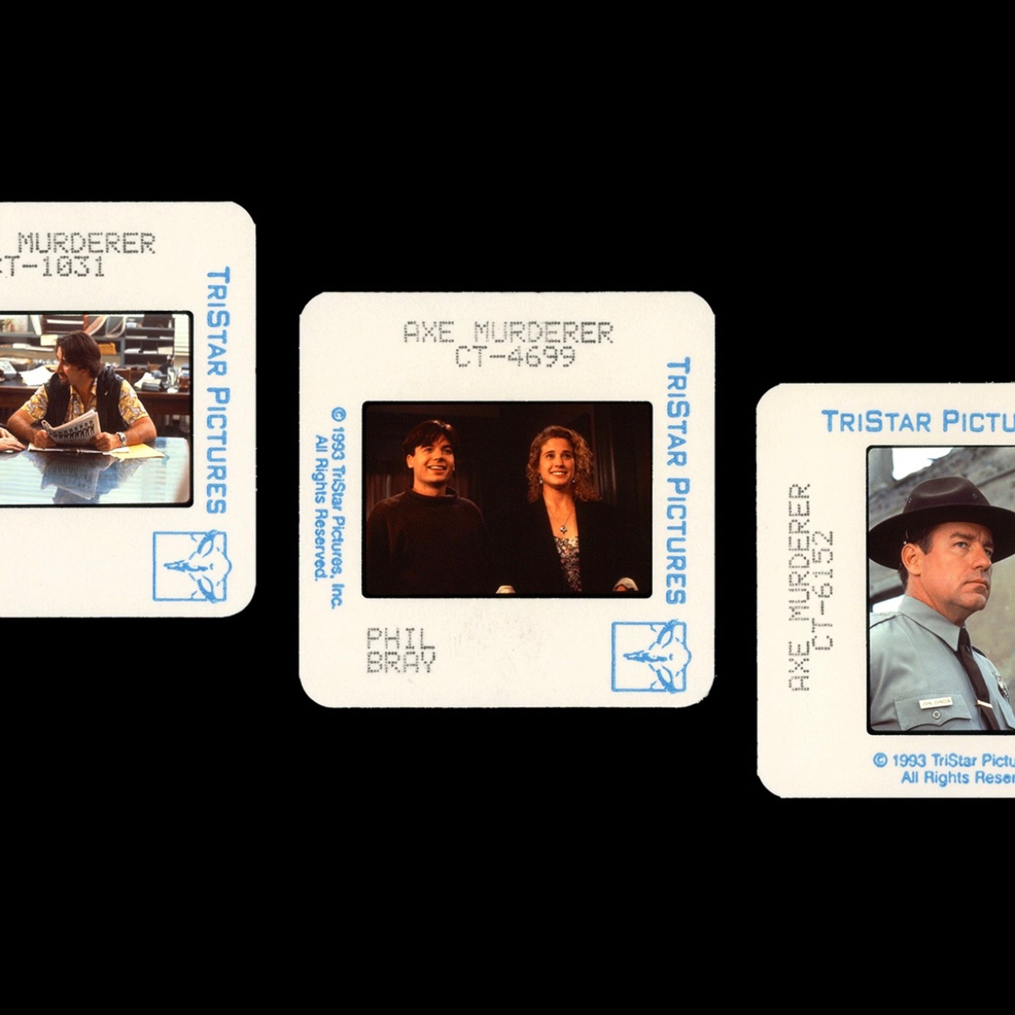 Publicity slides from SO I MARRIED AN AXE MURDERER, taken by Phil Bray. From left to right: Anthony LaPaglia sitting at a table; Mike Myers and Nancy Travis standing and smiling at something off-camera; Phil Hartman scowling in a police uniform.