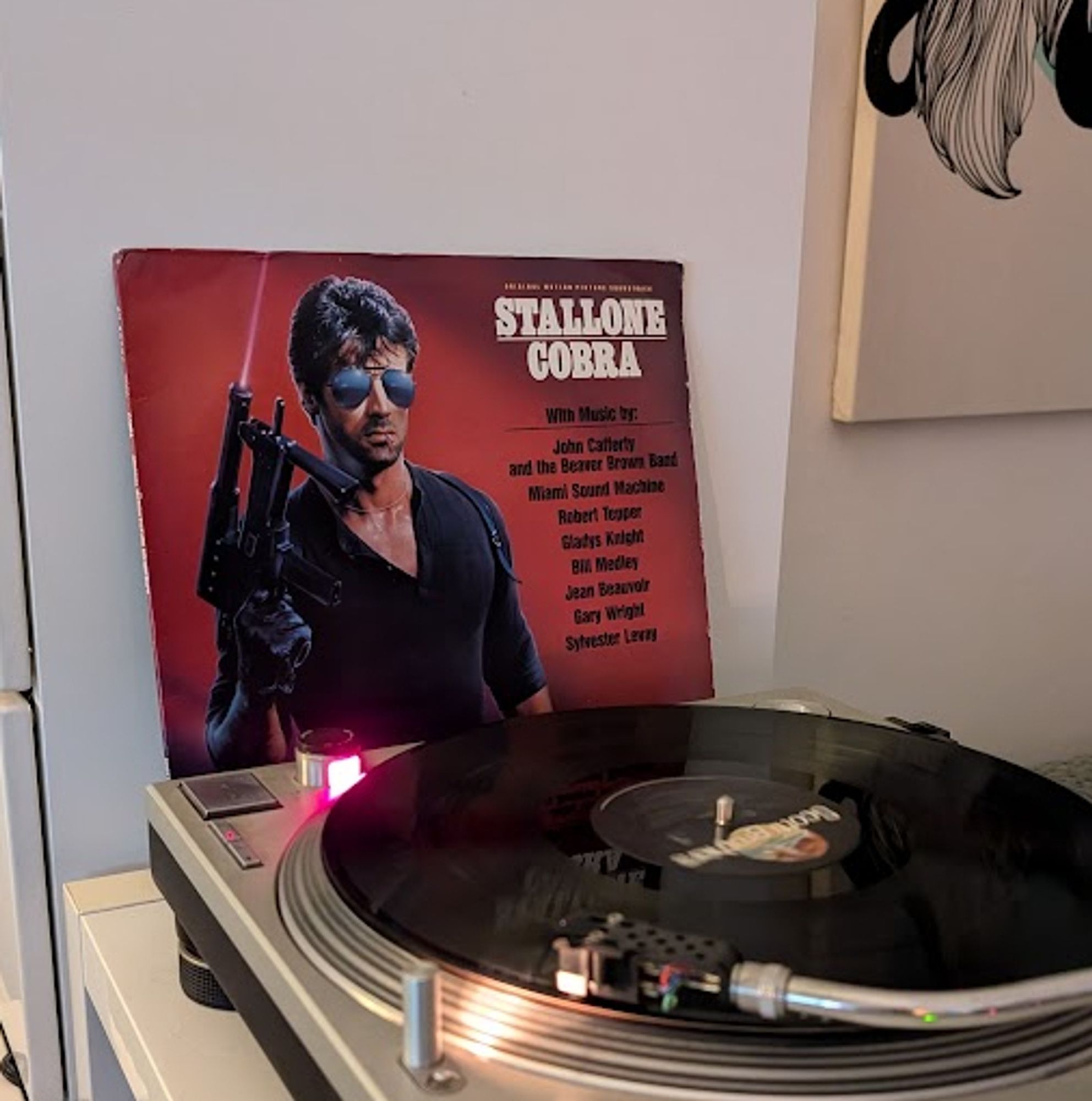 A record playing and the album cover to the soundtrack for Cobra, the movie, in the back ground