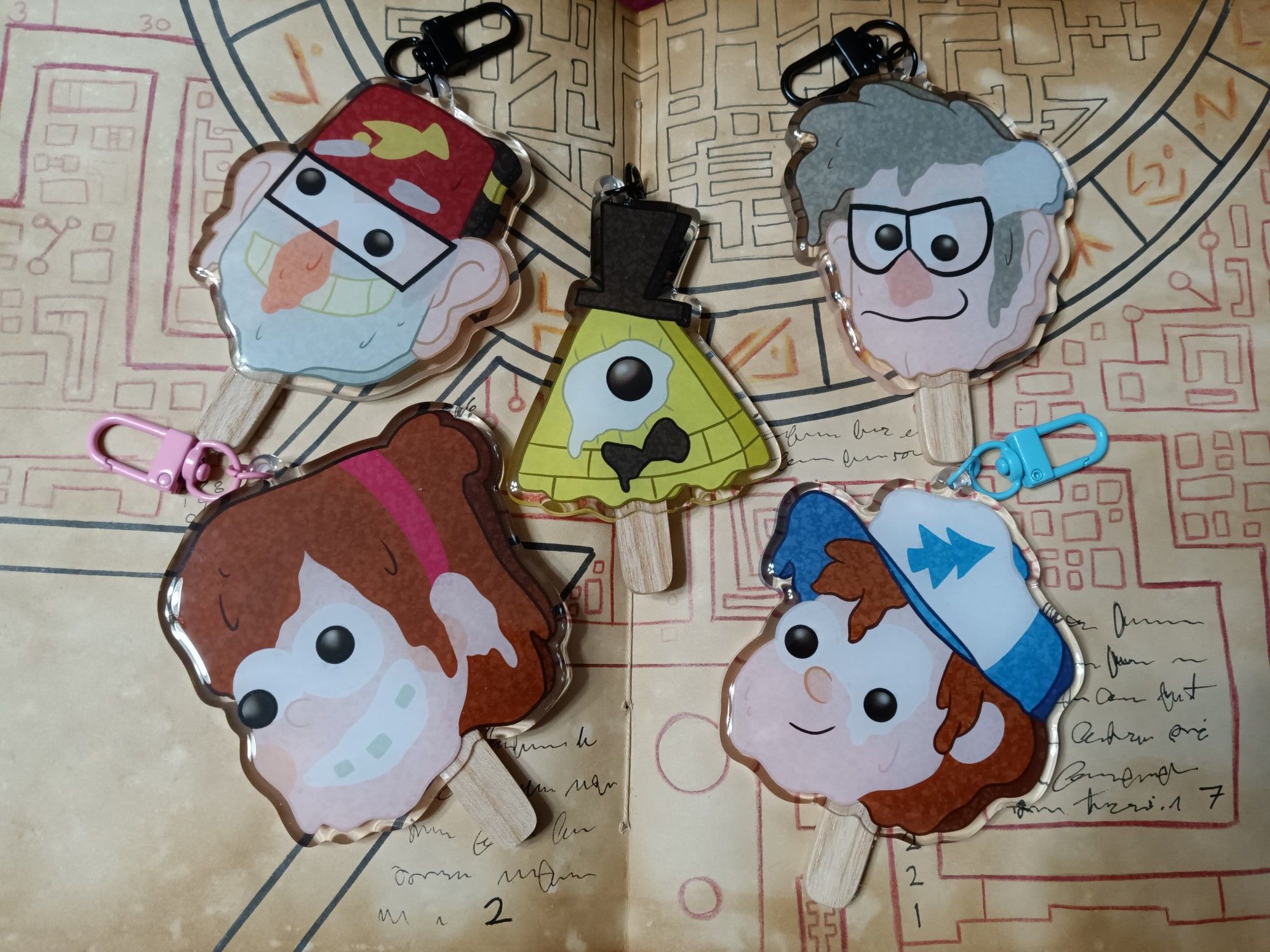 A group of acrylic charms made to look like melting popsicles. They depict characters from the show Gravity Falls.