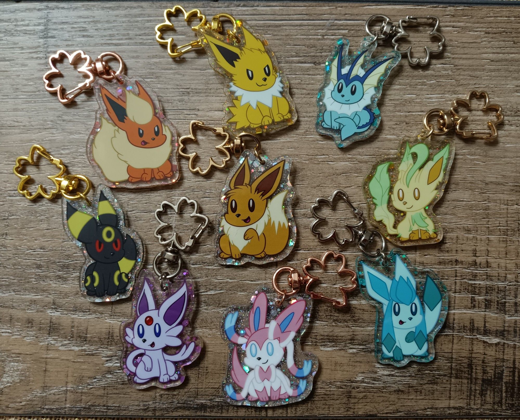 Photo is of acrylic charms based on Eevee and it's evolutions from Pokemon. Each charm depicts one evolution and is glittery.