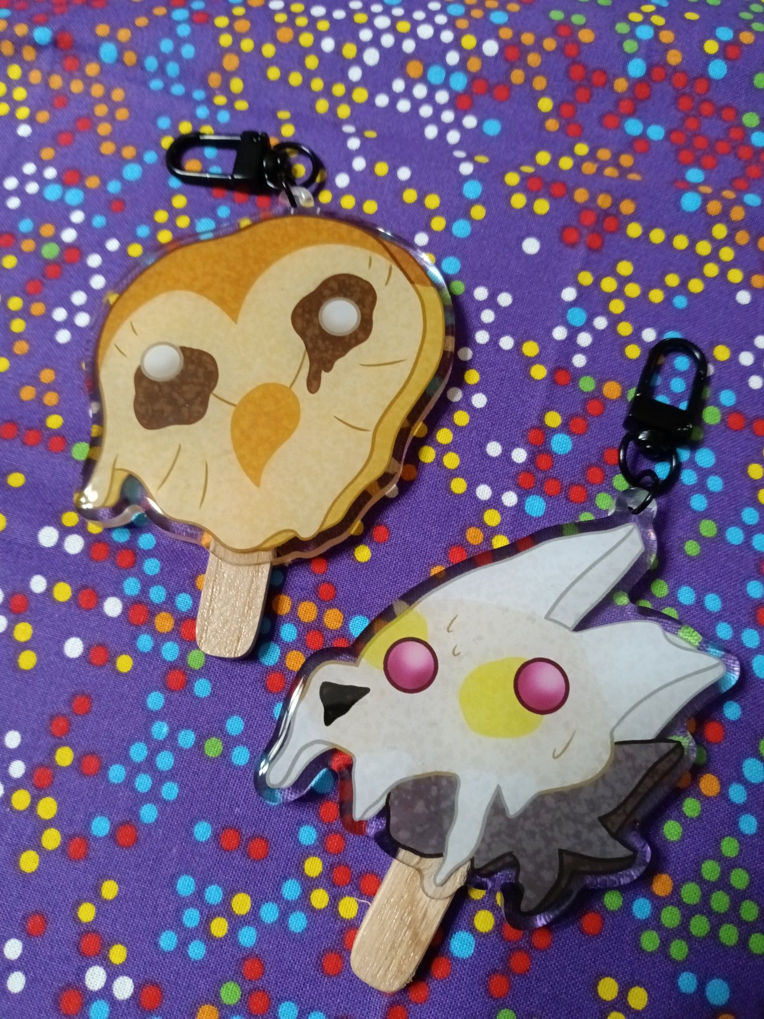 A group of acrylic charms made to look like melting popsicles. They depict Hooty and King from the show The Owl House.