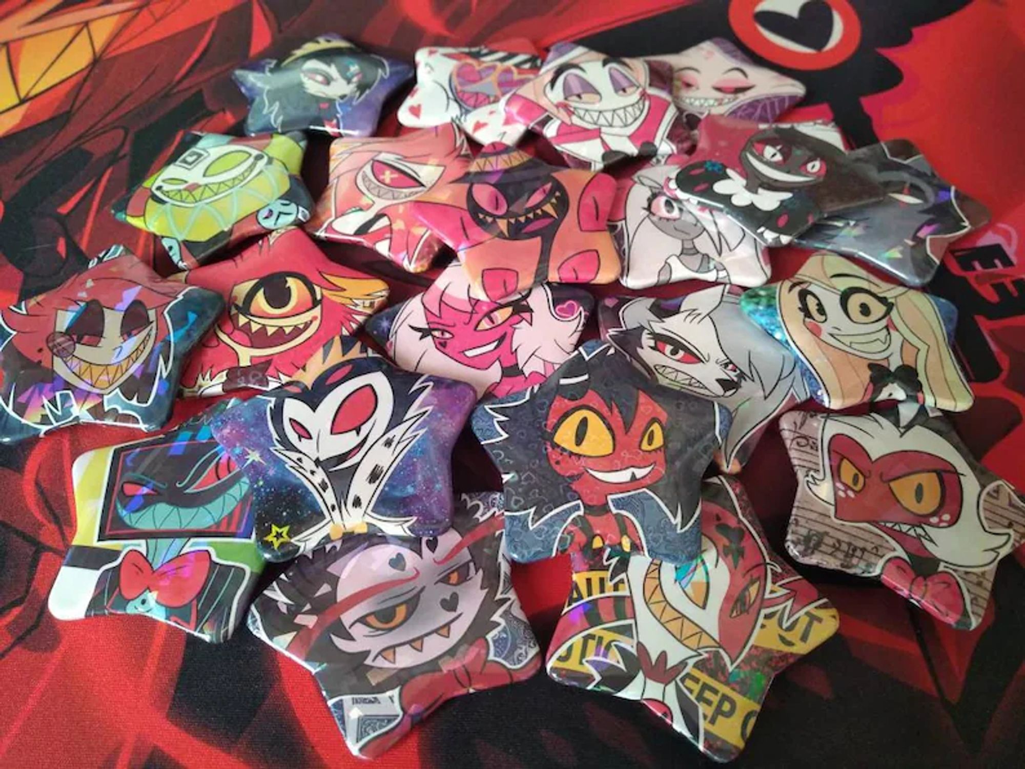 Star shaped pin badges featuring characters from Hazbin Hotel and Helluva Boss