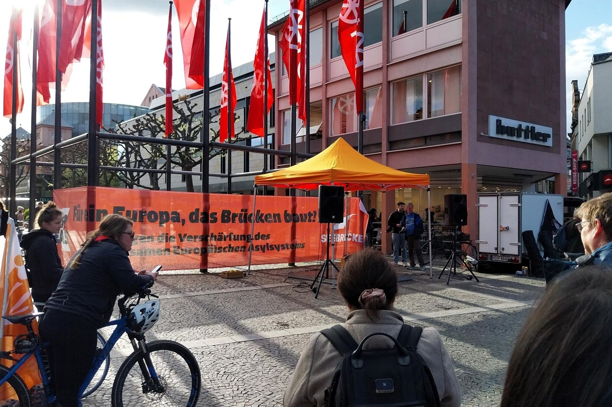 An den Fahnenmasten am Domplatz in Mainz ein großes oranges Transpi:

Für ein Europa, das Brücken baut!
Gegen die Verschärfung des
gemeinsamen Europäischen Asylsystems

rechts Seebrücke Logo