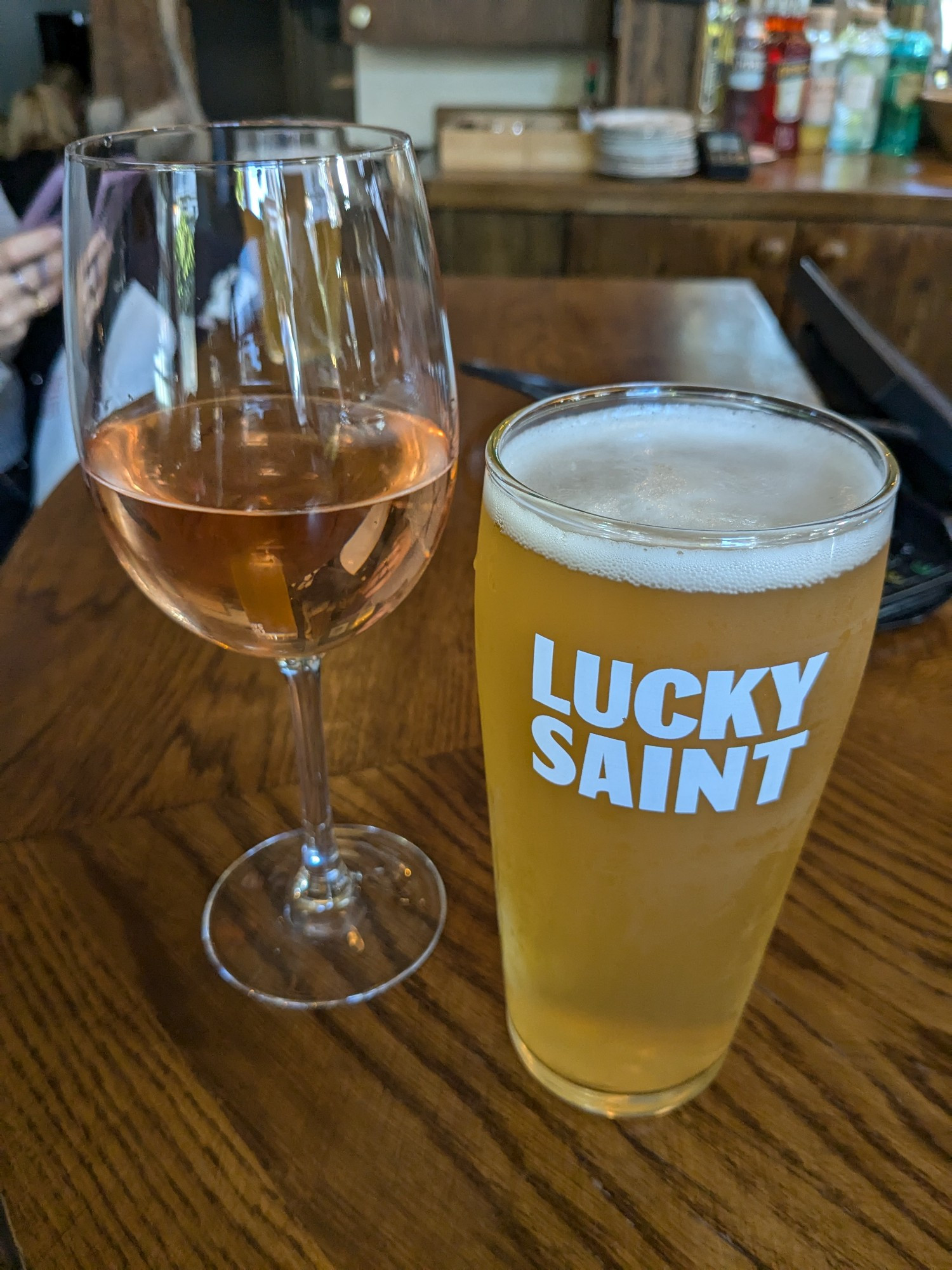 A glass of Rosé and a pint of Lucky Saint resting on a bar in the Lucky Saint pub in London.