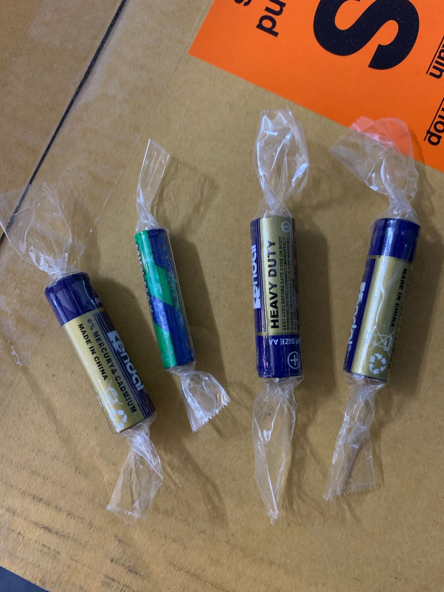 Four batteries on a cardboard box, each individually wrapped in tape to protect the positive and negative leads making them looking like wrapped hard candies.