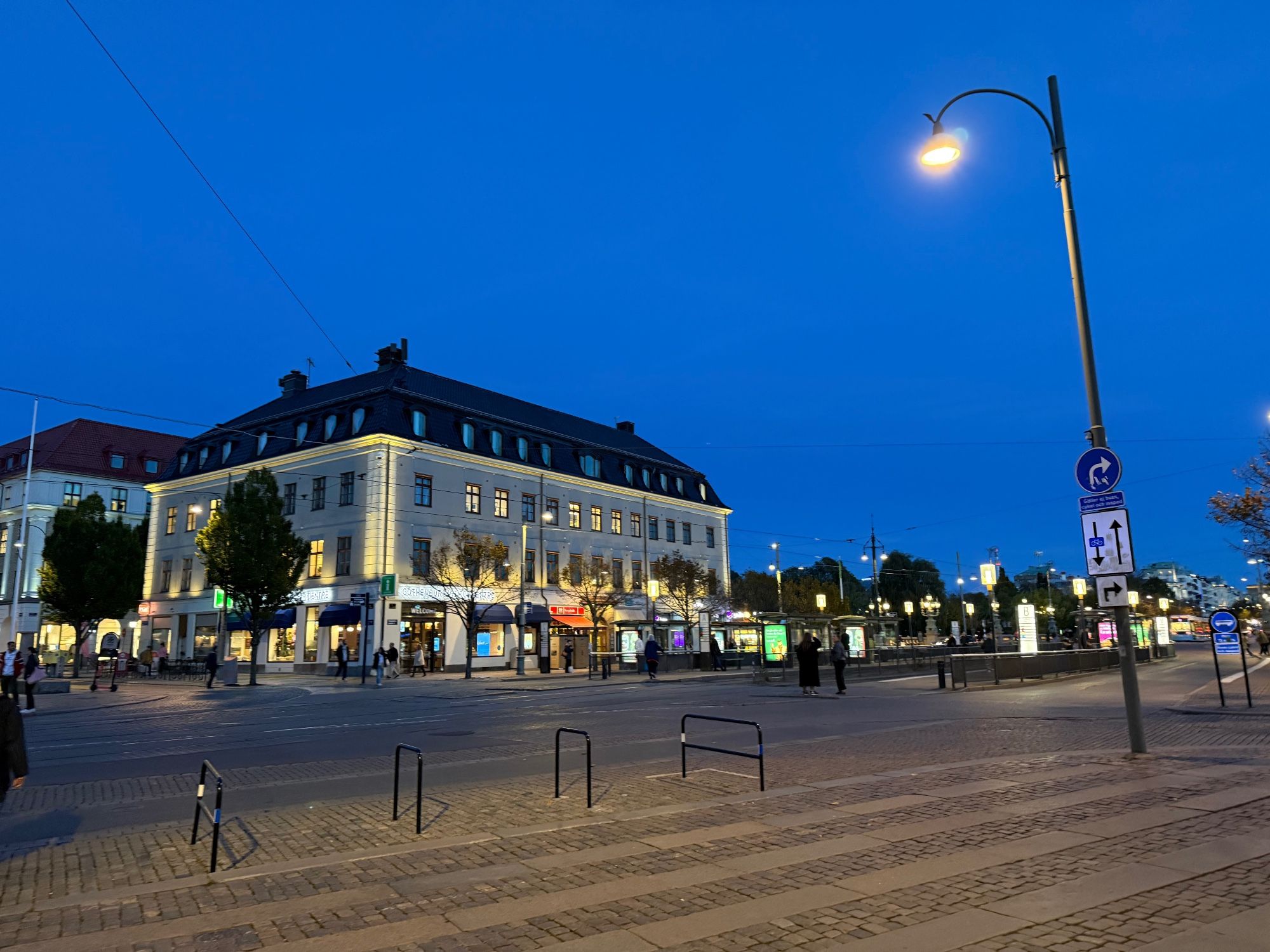 An evening scene on the Kungsportplatsen in Göteborg, with a building lit up and a cobblestone street