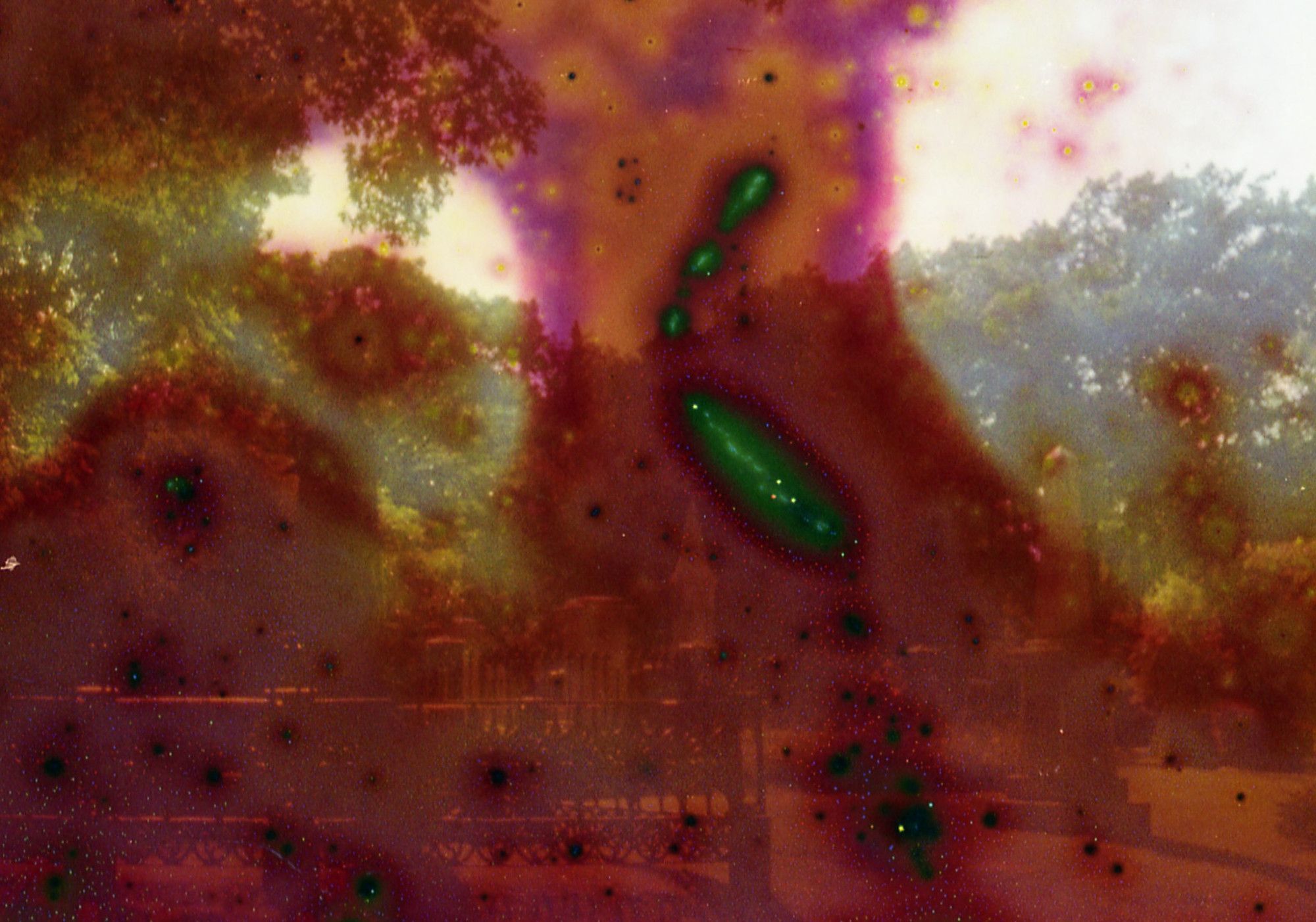 Expired film photograph of a cemetery with red and green color distortion blobs spreading across it