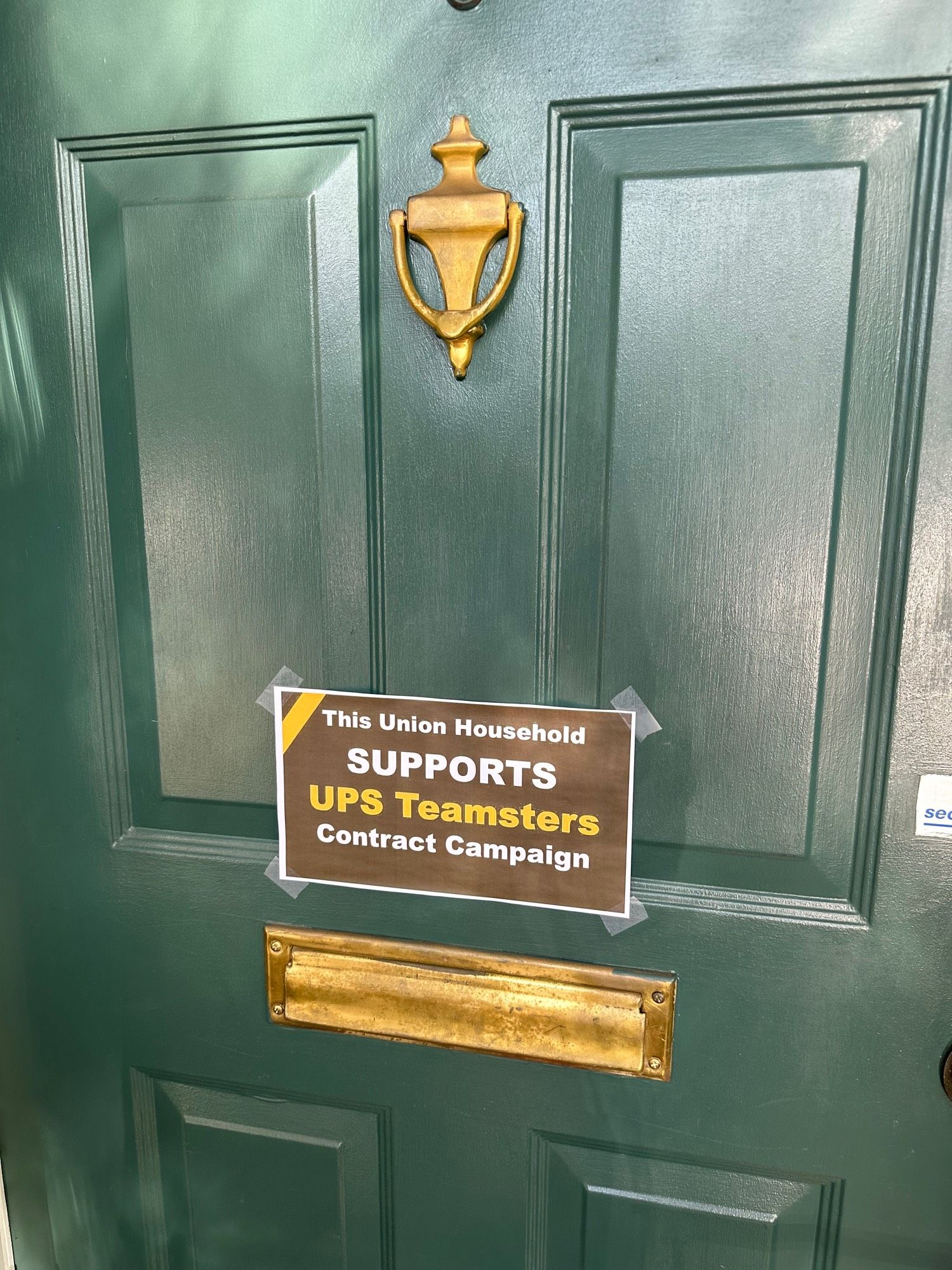 Sign on front door with mail slot, supporting Teamsters contract bargaining at UPS. 