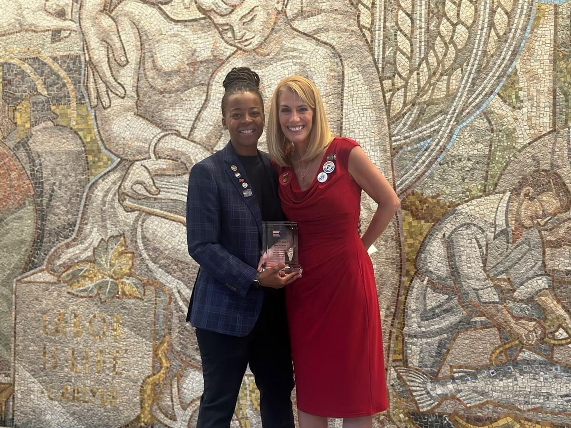 Keturah Johnson and Sara Nelson standing with the Pride at Work Solidarity Award in front of Labor is Life mural at the AFL-CIO.